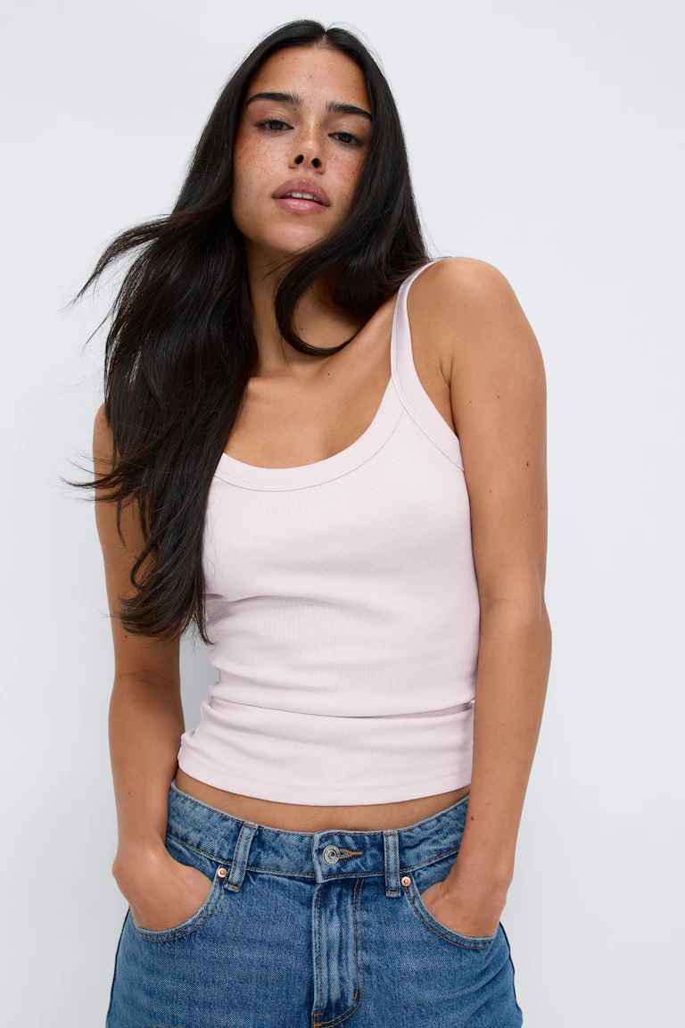 Lys rosa ribbestrikket tanktop med rund hals kombinert med mellomblå jeans med høy midje.