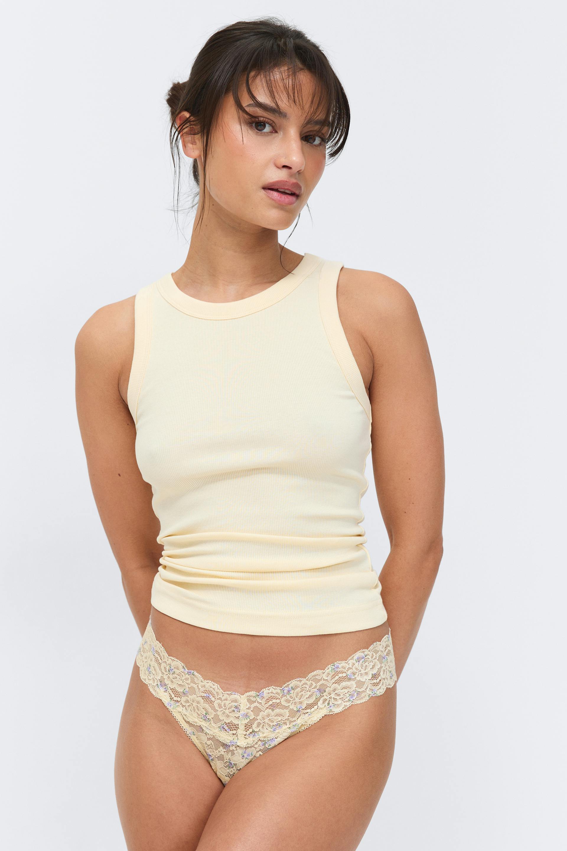 Hellgelbes, geripptes, ärmelloses Tank-Top mit Rundhalsausschnitt, gepaart mit einem passenden, hellgelben, floralen Spitzen-Tanga mit tiefem Ausschnitt.