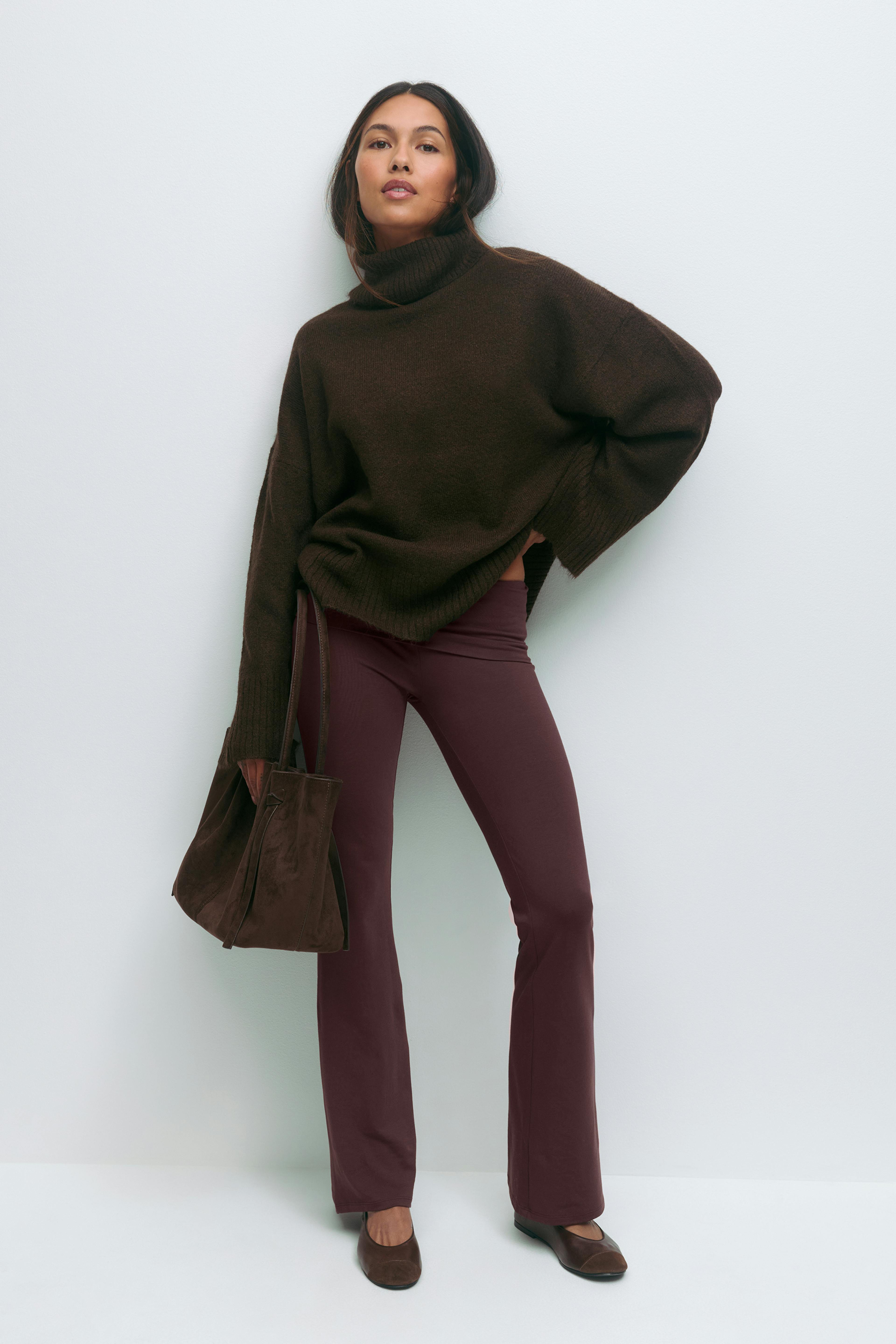 Mørkebrun oversize rullekravesweater med ribbede manchetter, sat sammen med bordeaux slim-fit flared bukser; mørkebrun ruskindstaske og brune lavhælede ruskindspumps.