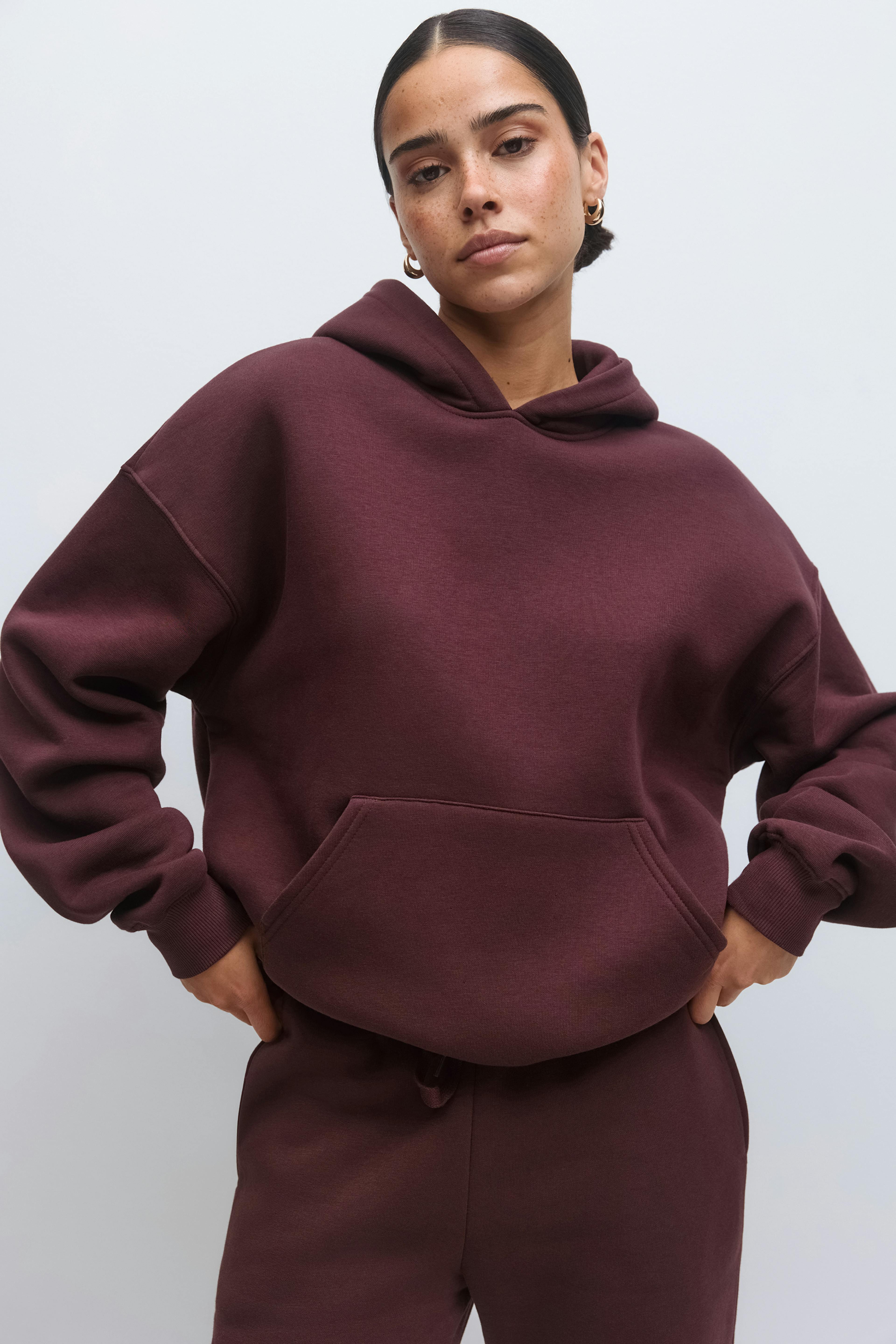 Sweat à capuche surdimensionné bordeaux avec poche kangourou, associé à un pantalon de survêtement bordeaux assorti.