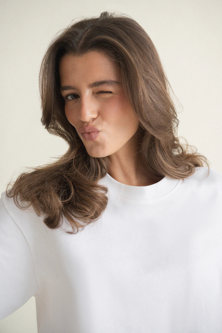 Oversized white short-sleeve T-shirt paired with light beige pinstripe wide-leg trousers.