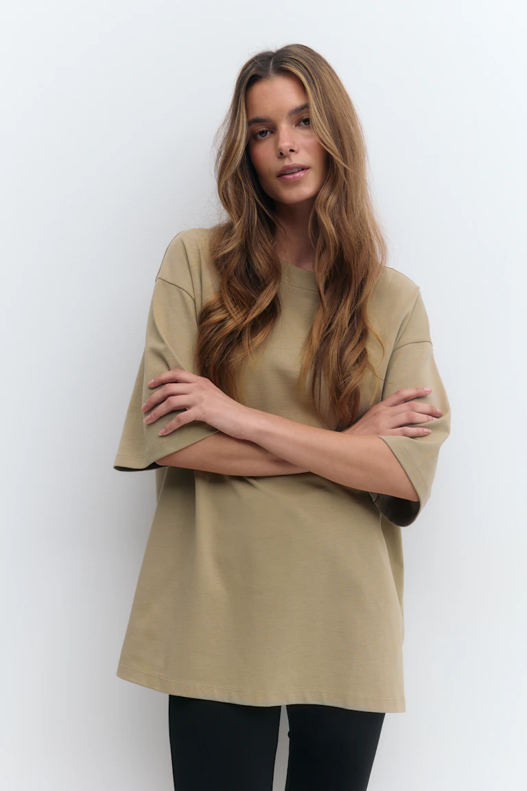 Oversized beige kortärmad T-shirt med rund halsringning kombinerad med smala svarta leggings.