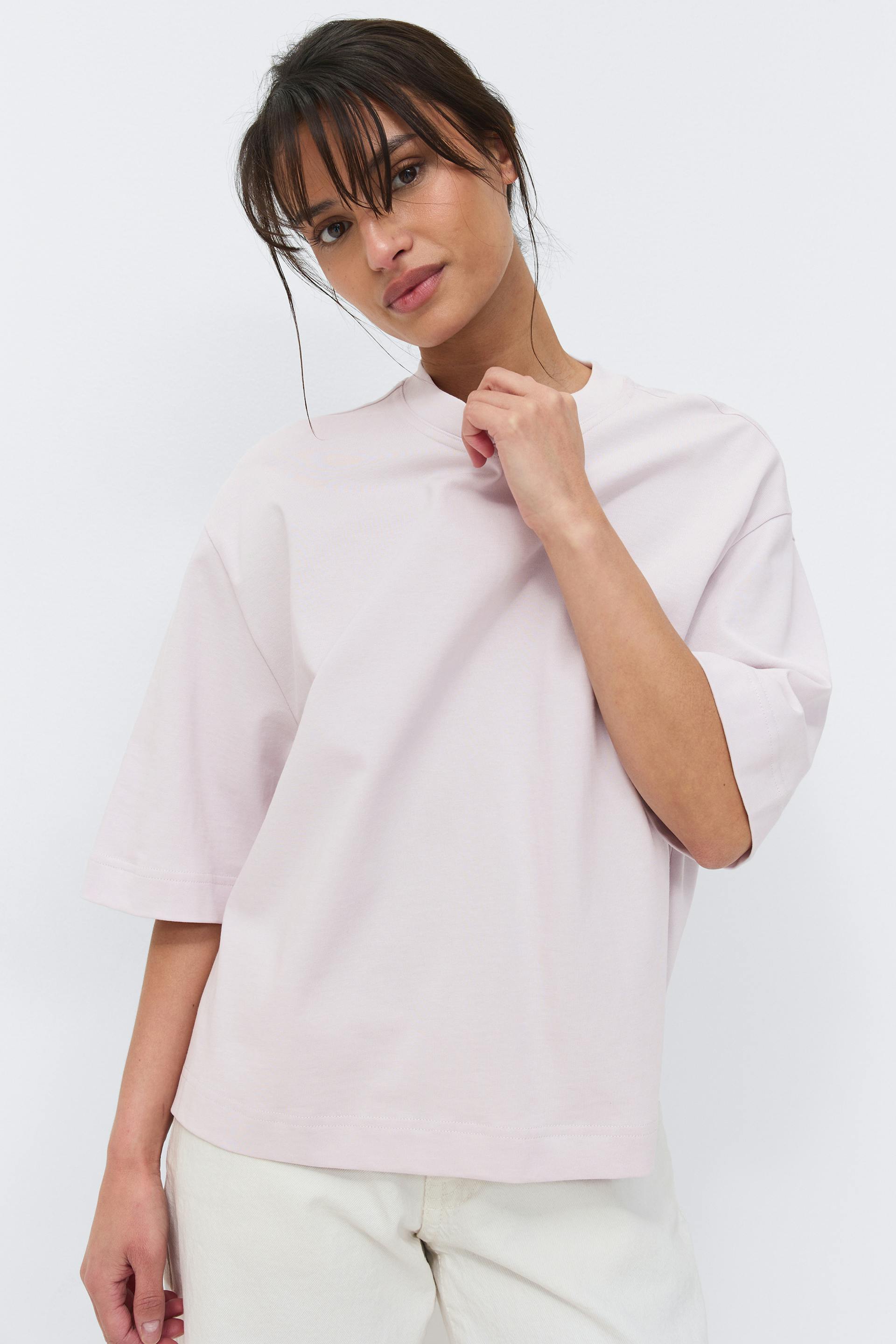 Lyserød oversized T-shirt med rund hals og albuelange ærmer, sat sammen med råhvide bukser med afslappet pasform.