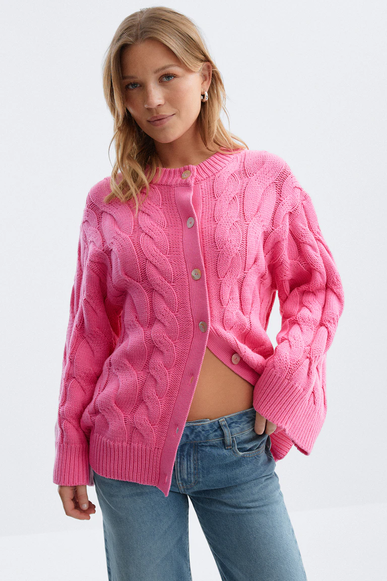 Knalroze vest met knoopsluiting en geribde boorden en zoom, gecombineerd met een blauwe spijkerbroek.