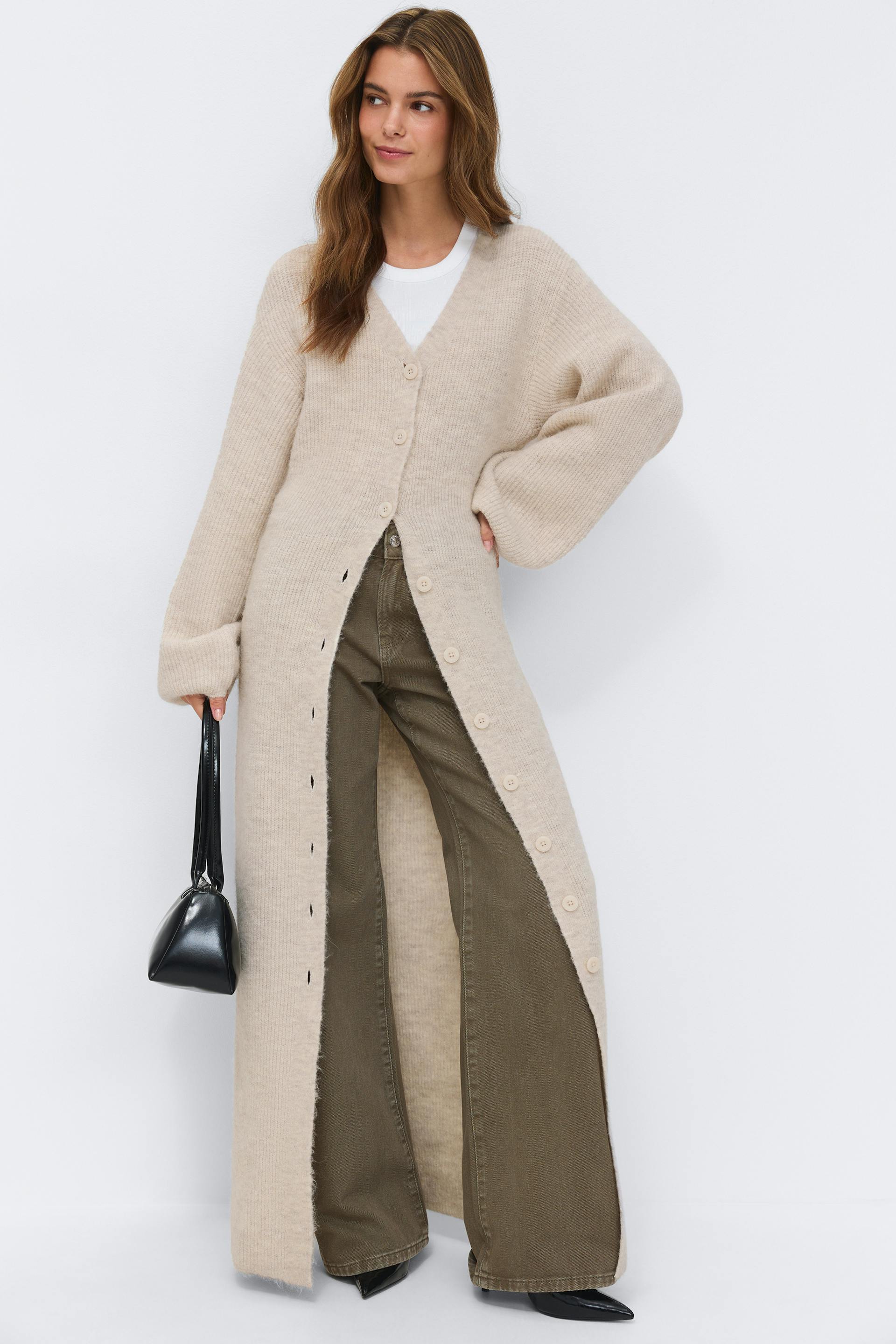 Beige ribbed knit maxi button-front dress with V-neck and long balloon sleeves, paired with dark brown T-strap low-heeled pumps.