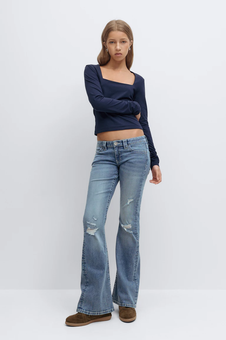 Navy long-sleeve square-neck cropped top, light-wash distressed flared jeans, and brown suede slip-on shoes.
