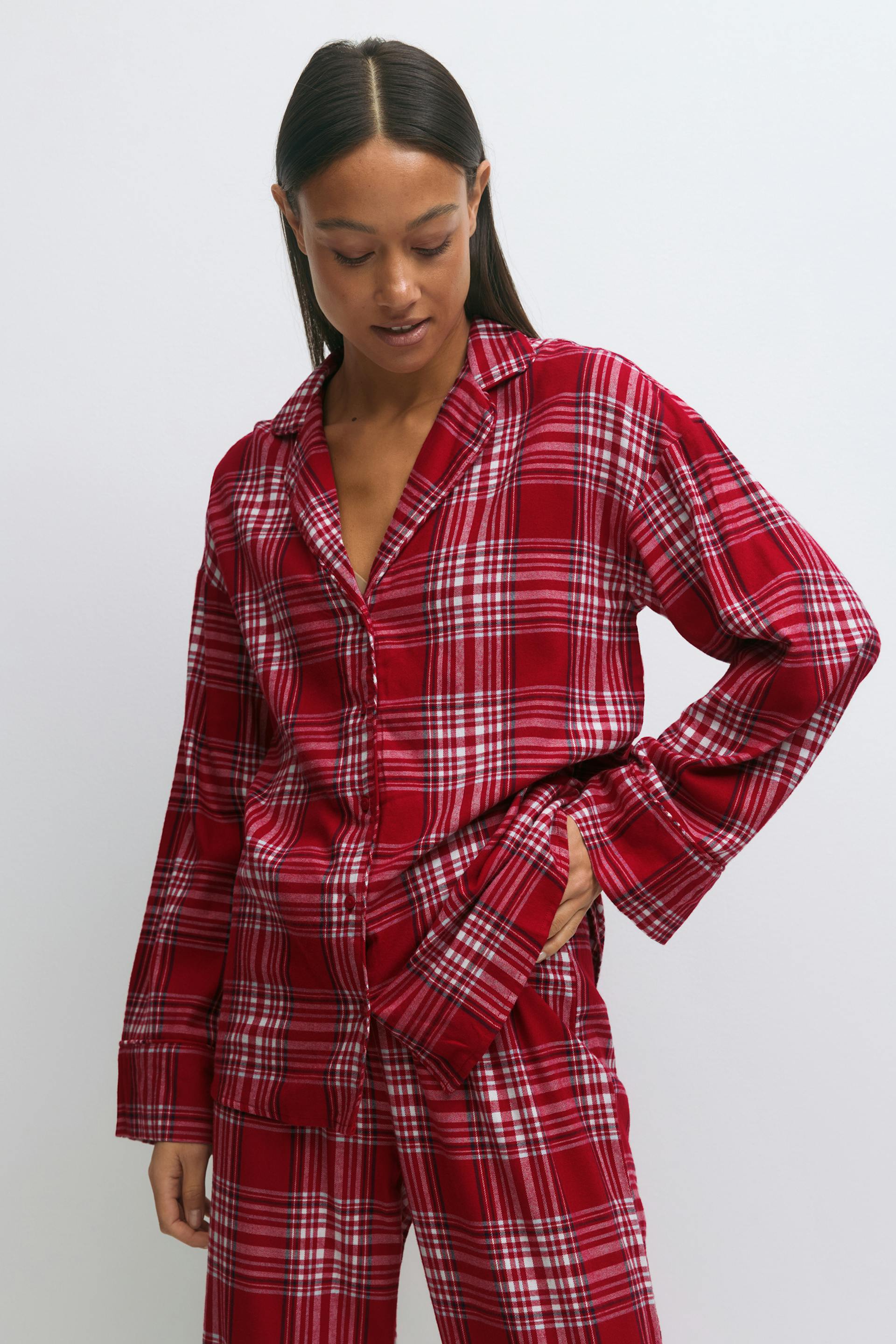 Red-and-white plaid flannel two-piece sleep set comprising a long-sleeve collared button-up shirt and matching relaxed-fit trousers.