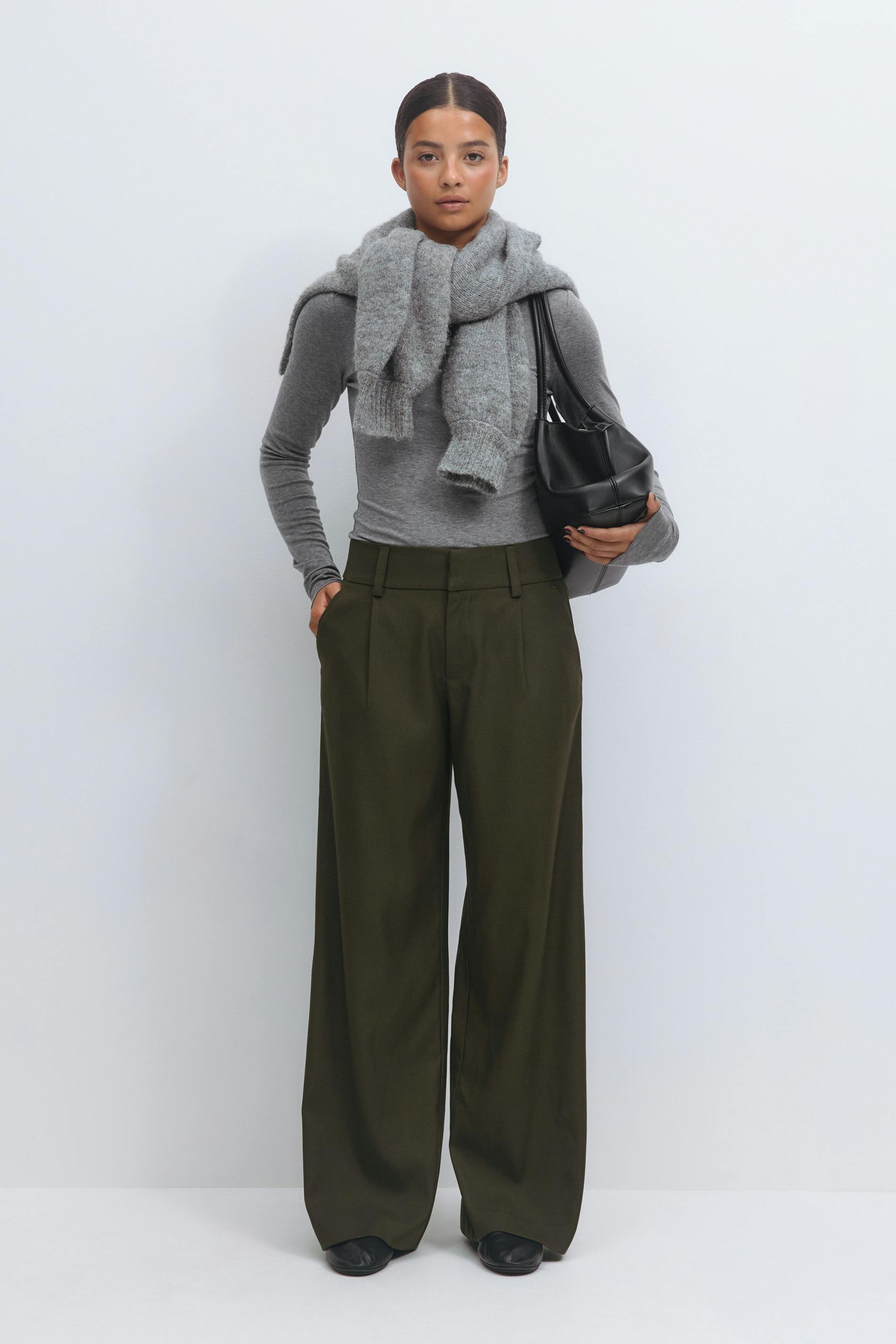 Fitted grey long-sleeve top with a chunky grey knit scarf, high-waist olive-green wide-leg trousers, black leather shoulder bag and black leather shoes.