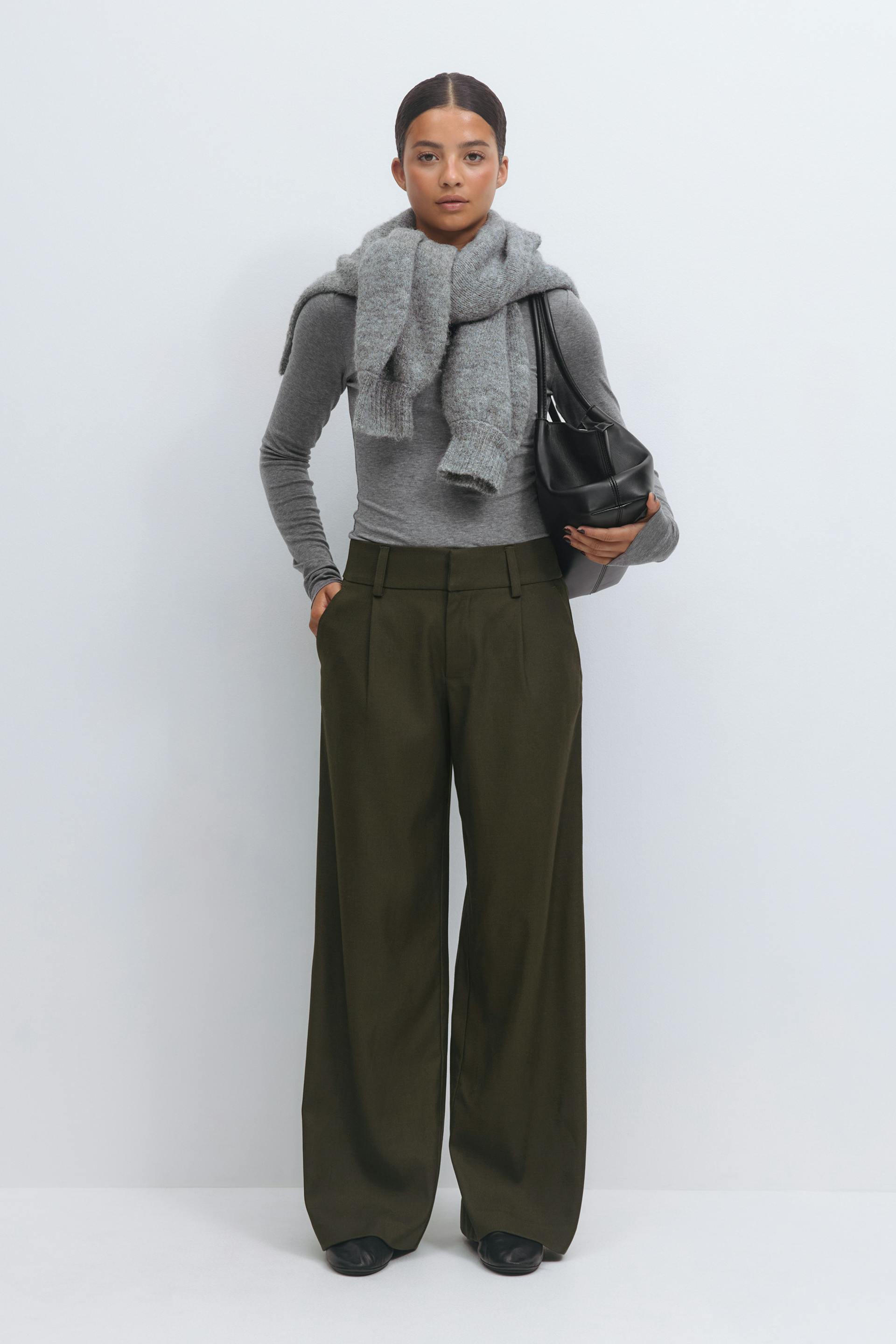 Fitted grey long-sleeve top with a chunky grey knit scarf, high-waist olive-green wide-leg trousers, black leather shoulder bag and black leather shoes.