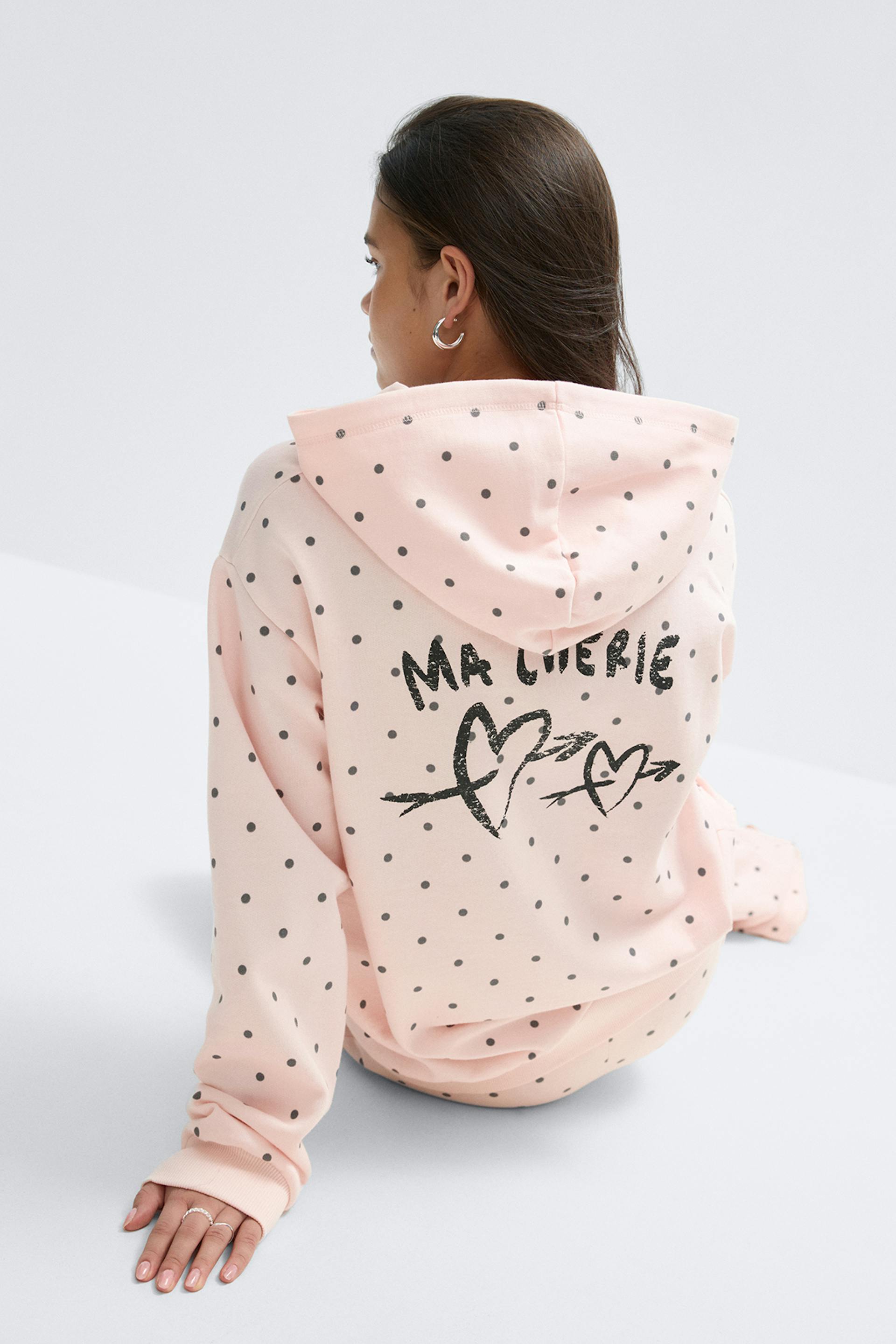 Sweat à capuche rose pâle et jogging assorti à motifs de petits pois noirs ; le dos du sweat à capuche est orné d'un cœur noir en relief et du texte "MA CHERIE".