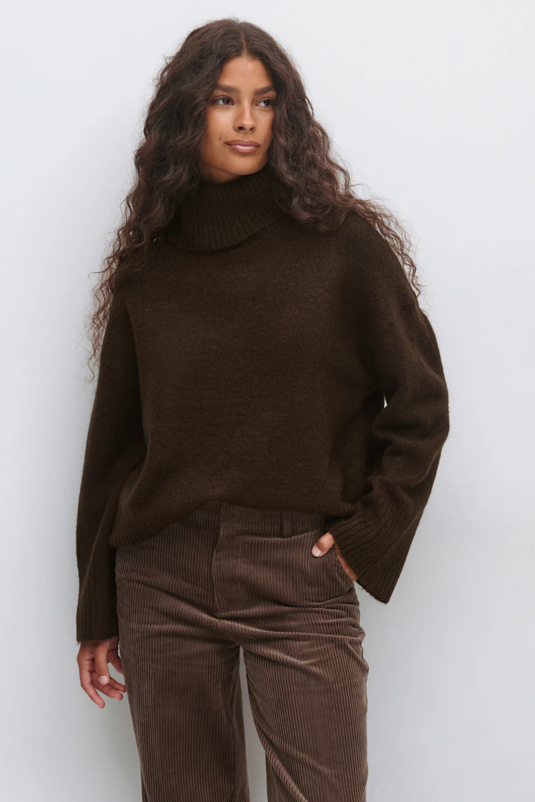 Pull à col roulé côtelé surdimensionné marron foncé à manches longues, associé à un pantalon en velours côtelé marron.
