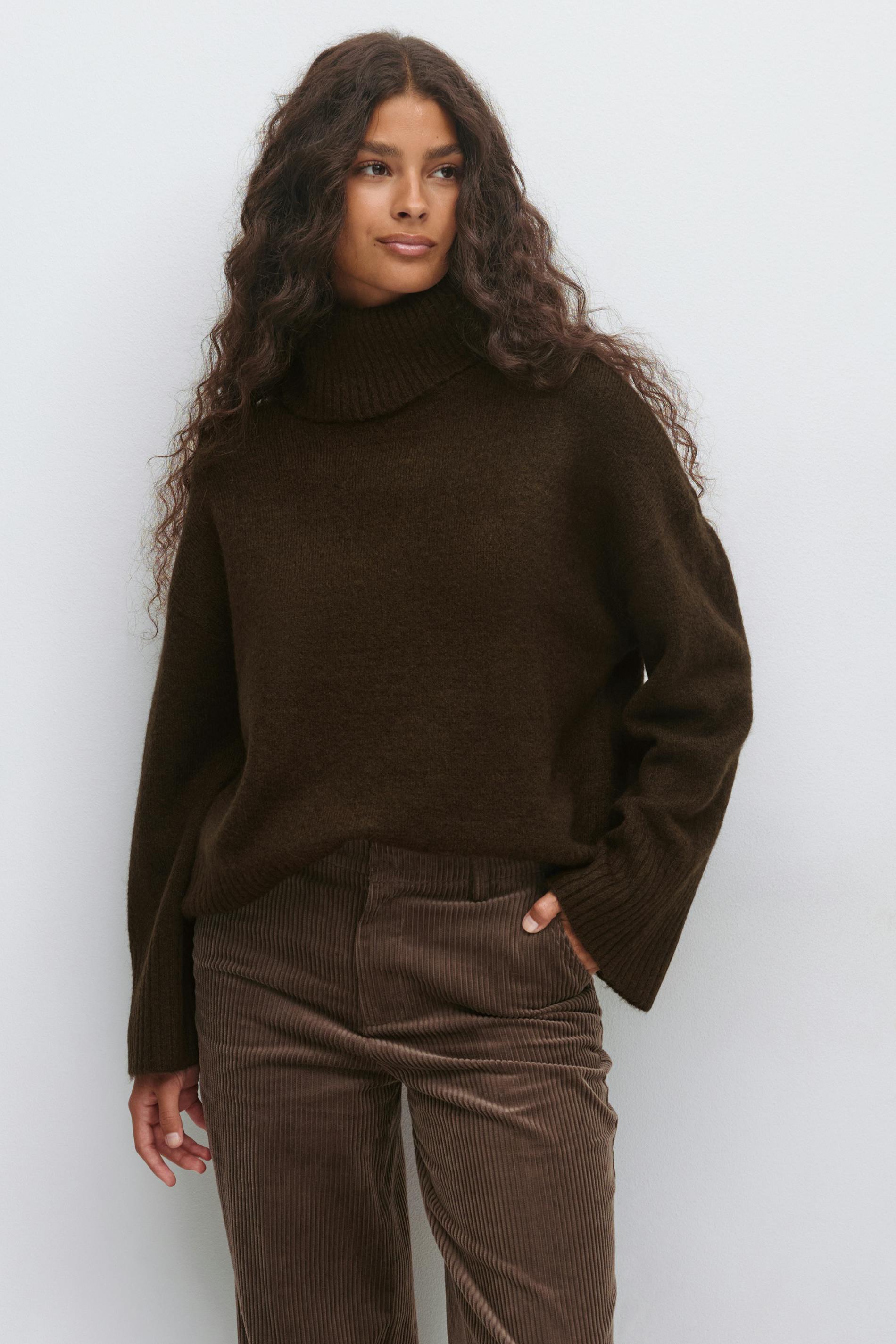 Dunkelbrauner übergroßer gerippter Rollkragenpullover mit langen Ärmeln, kombiniert mit einer braunen Kordhose.