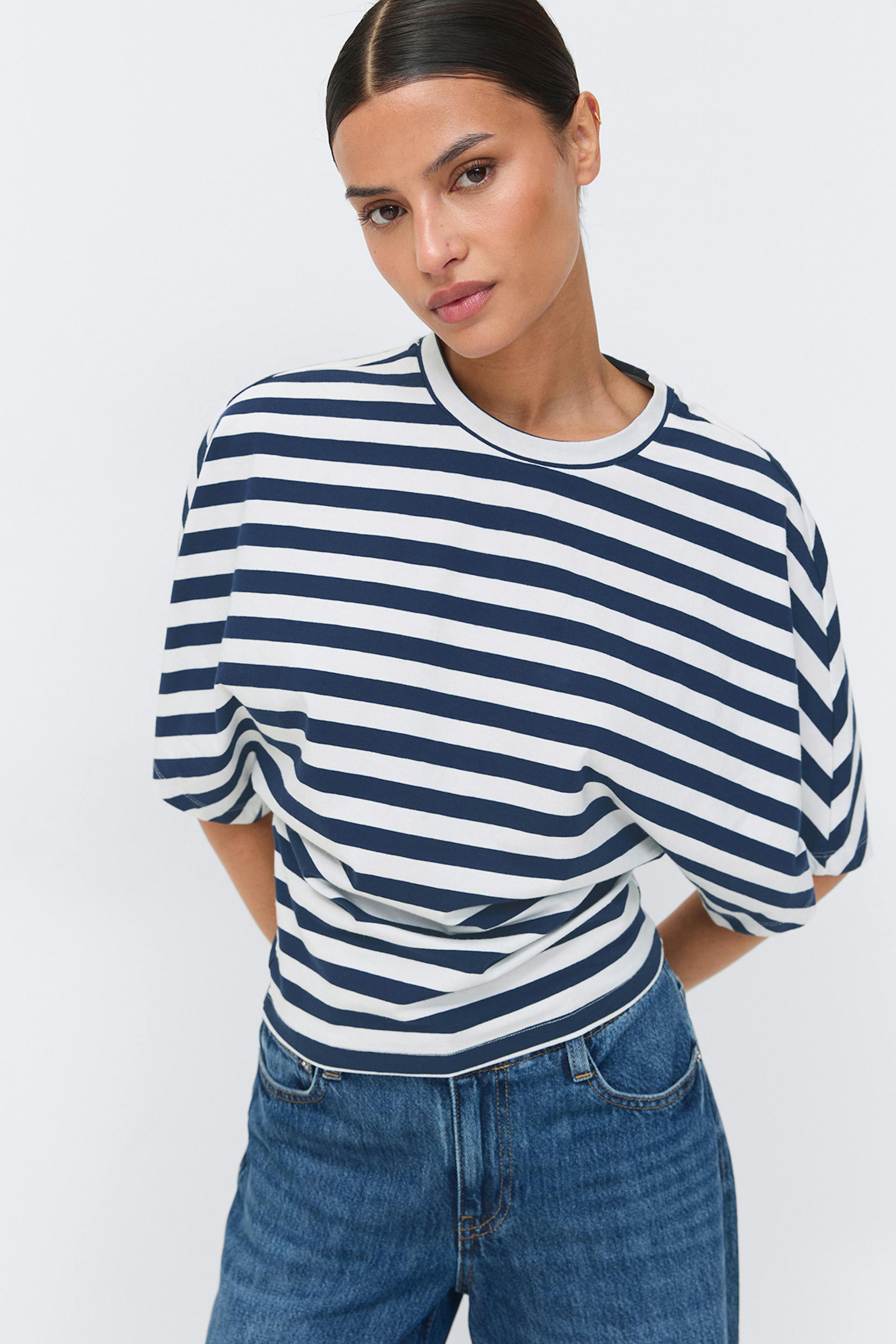 Kortärmad T-shirt med rund halsringning och horisontella ränder i marinblå och vit färg tillsammans med jeans i medium tvätt.