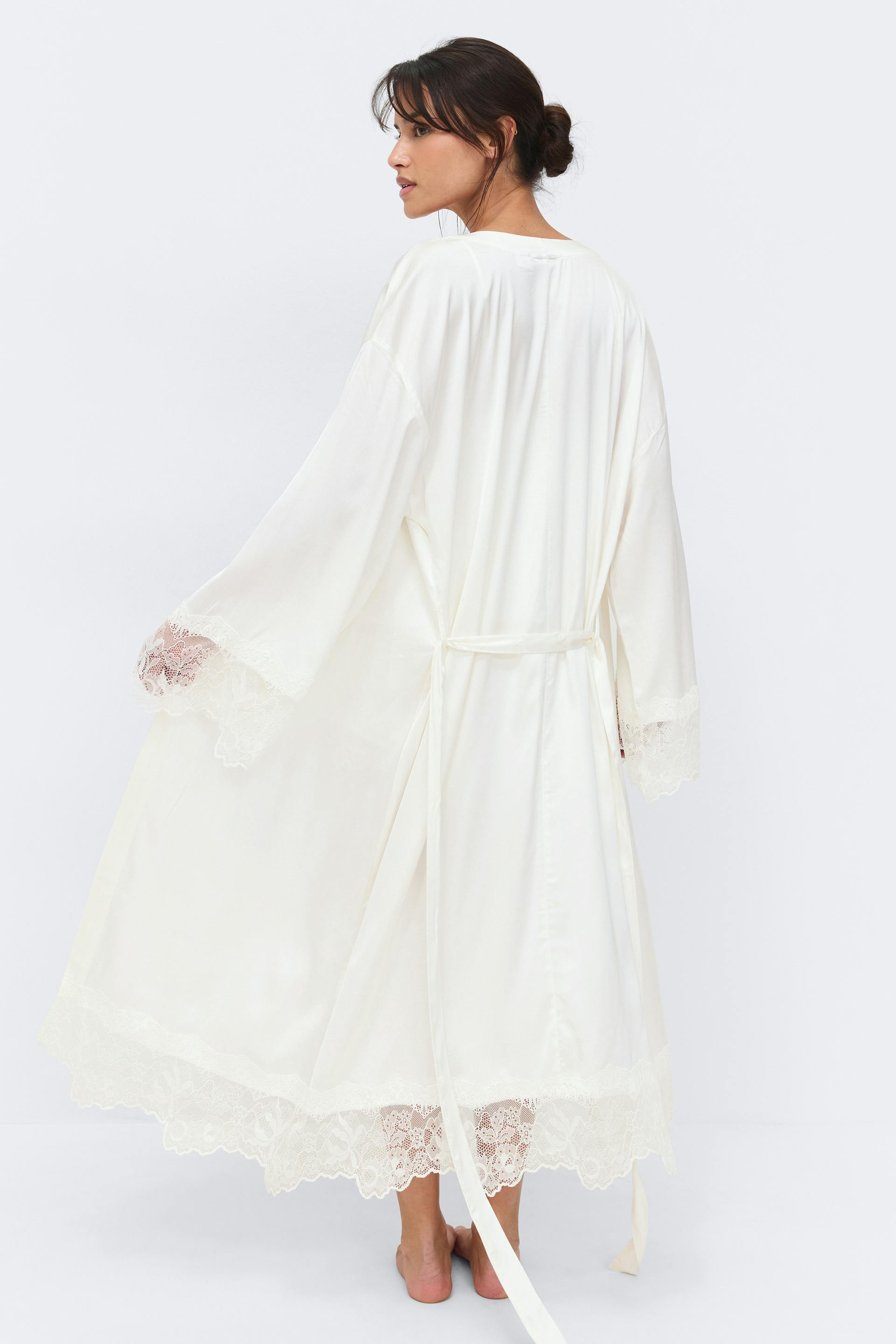 Ankellång elfenbensfärgad satinrock med vida ärmar, skulpterad spets i ärmslut och nederkant samt självknytande midjebälte.