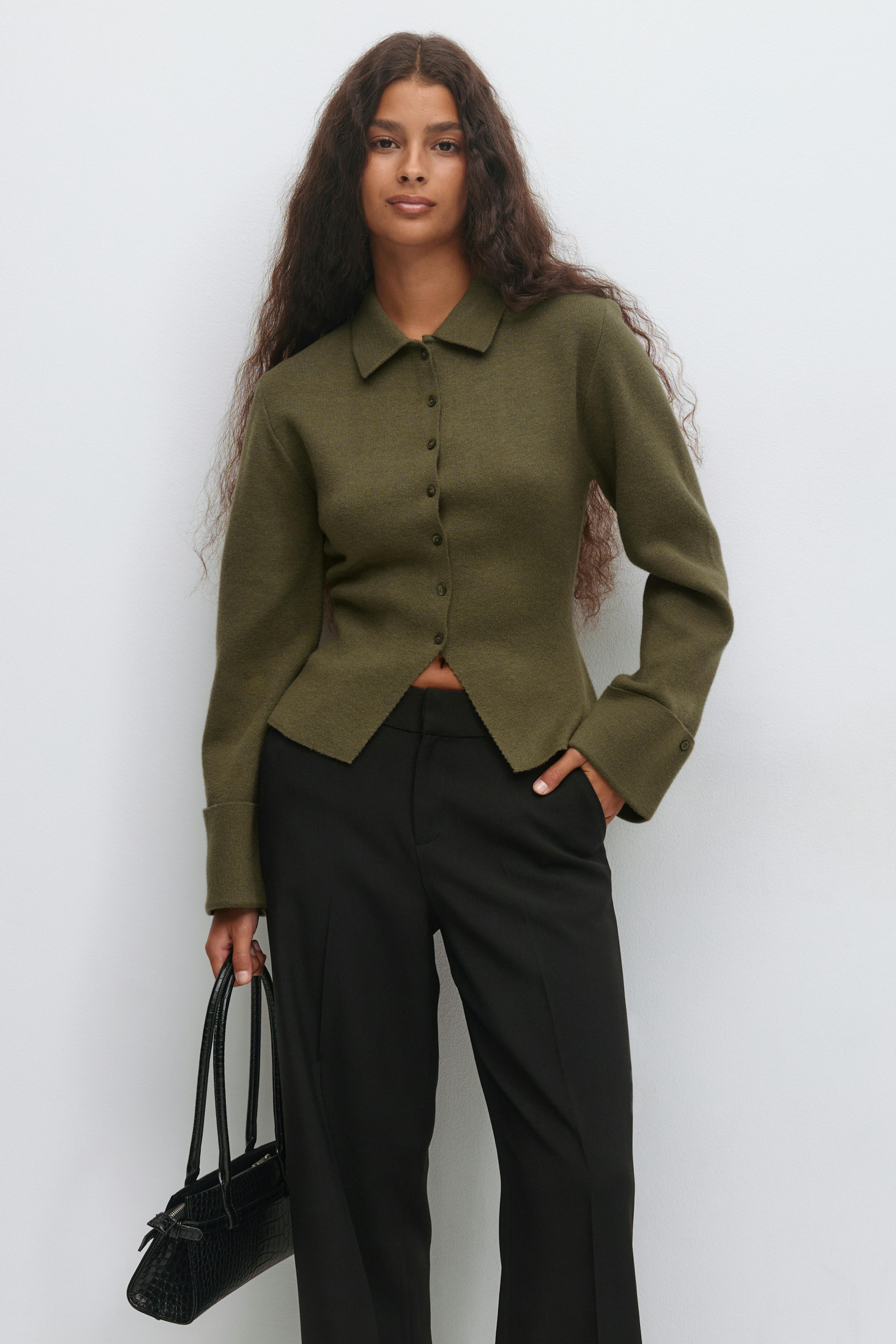 Olive-green collared button-up knit cardigan with long sleeves and shaped hem, paired with black tailored trousers and a small black croc-embossed handbag with top handles.