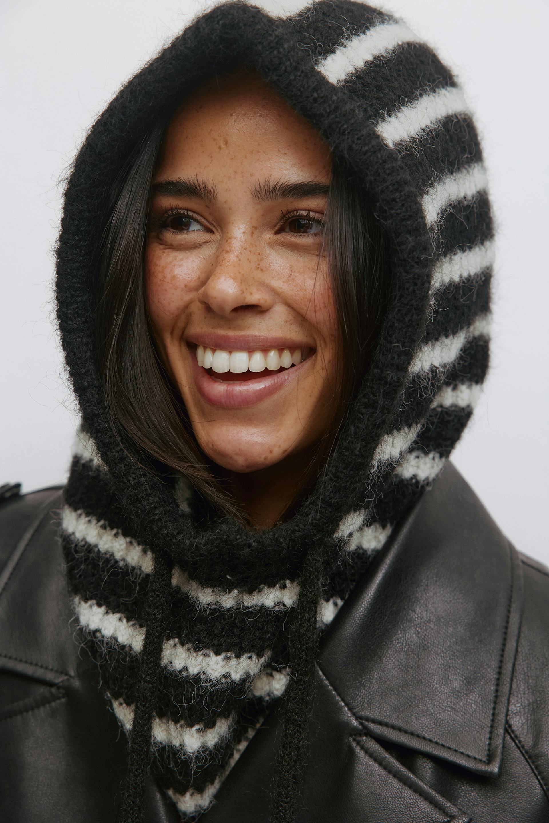 Mustavalkoraidallinen harjattu huppu, jossa on kiristysnauhat, ja musta nahkatakki.