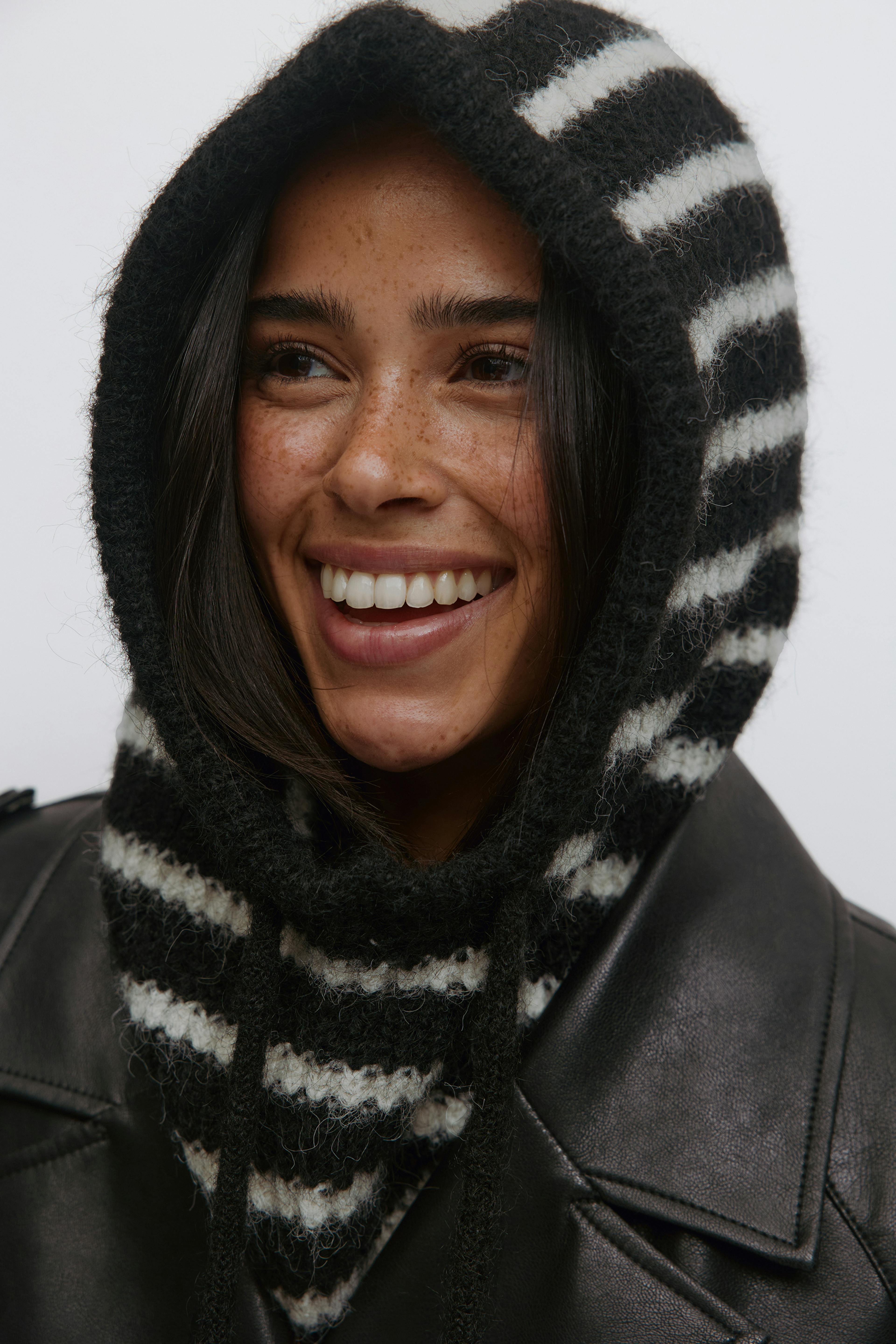 Mustavalkoraidallinen harjattu huppu, jossa on kiristysnauhat, ja musta nahkatakki.