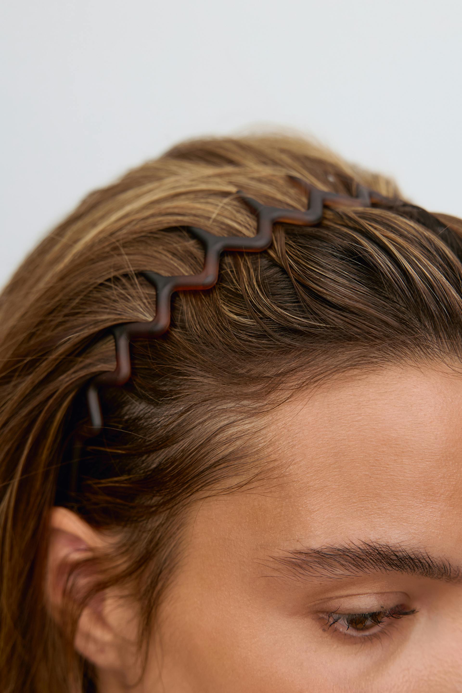 Wavy tortoiseshell plastic headband worn in the hair.