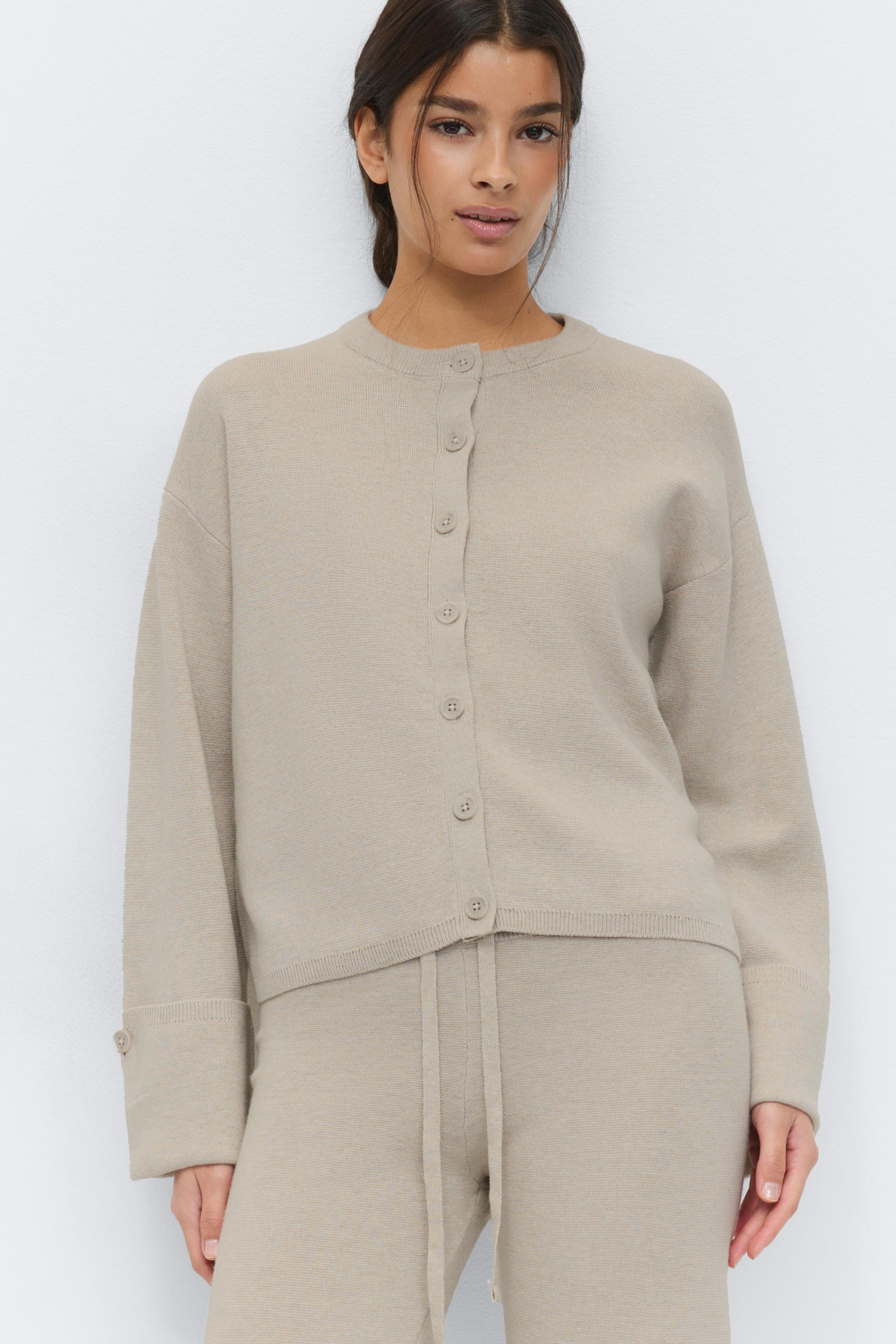 Light beige button-front knit cardigan with round neckline and cuffed sleeves, paired with matching drawstring knit trousers.