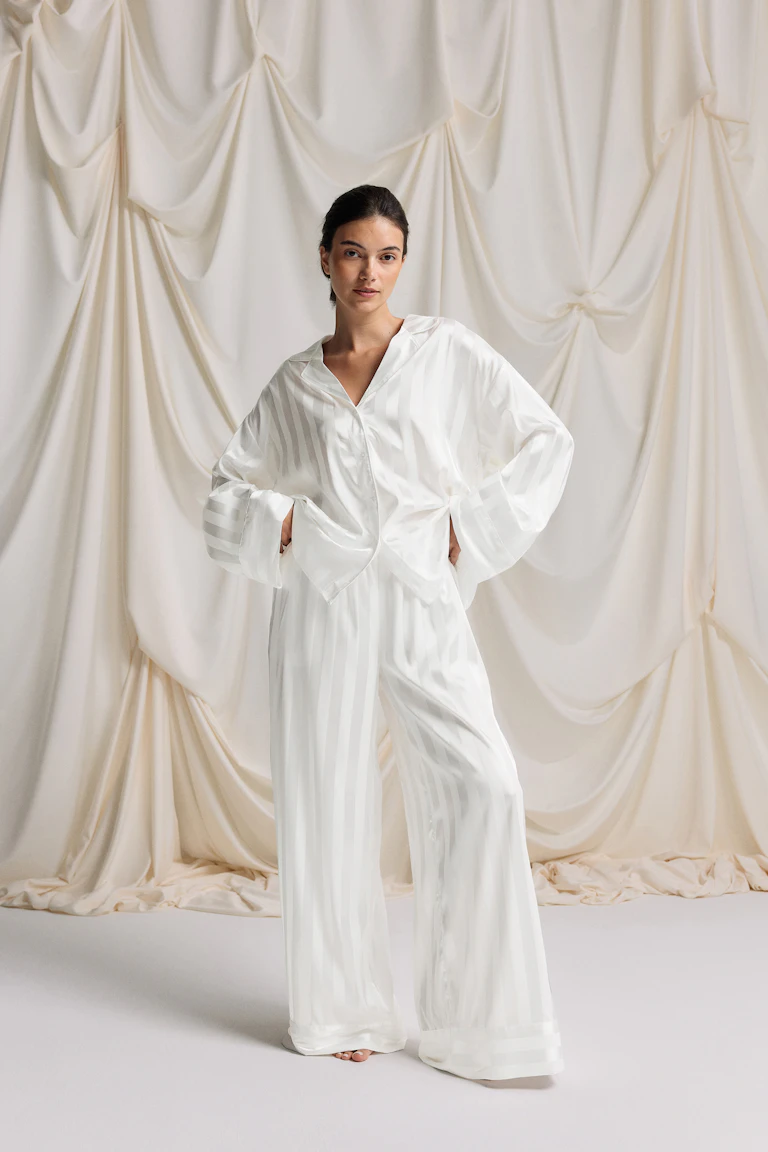 Pyjama-Set aus weißem Satin mit tonalen Streifen: übergroßes, langärmeliges Button-down-Hemd mit gekerbtem Kragen und passende Hose mit weitem Bein.