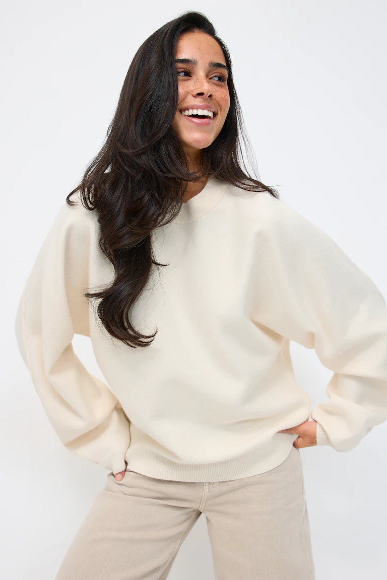 Cremefarvet oversize sweatshirt med rund hals og ribkant i krave, manchetter og forneden, sat sammen med lysbeige bukser med lige ben.