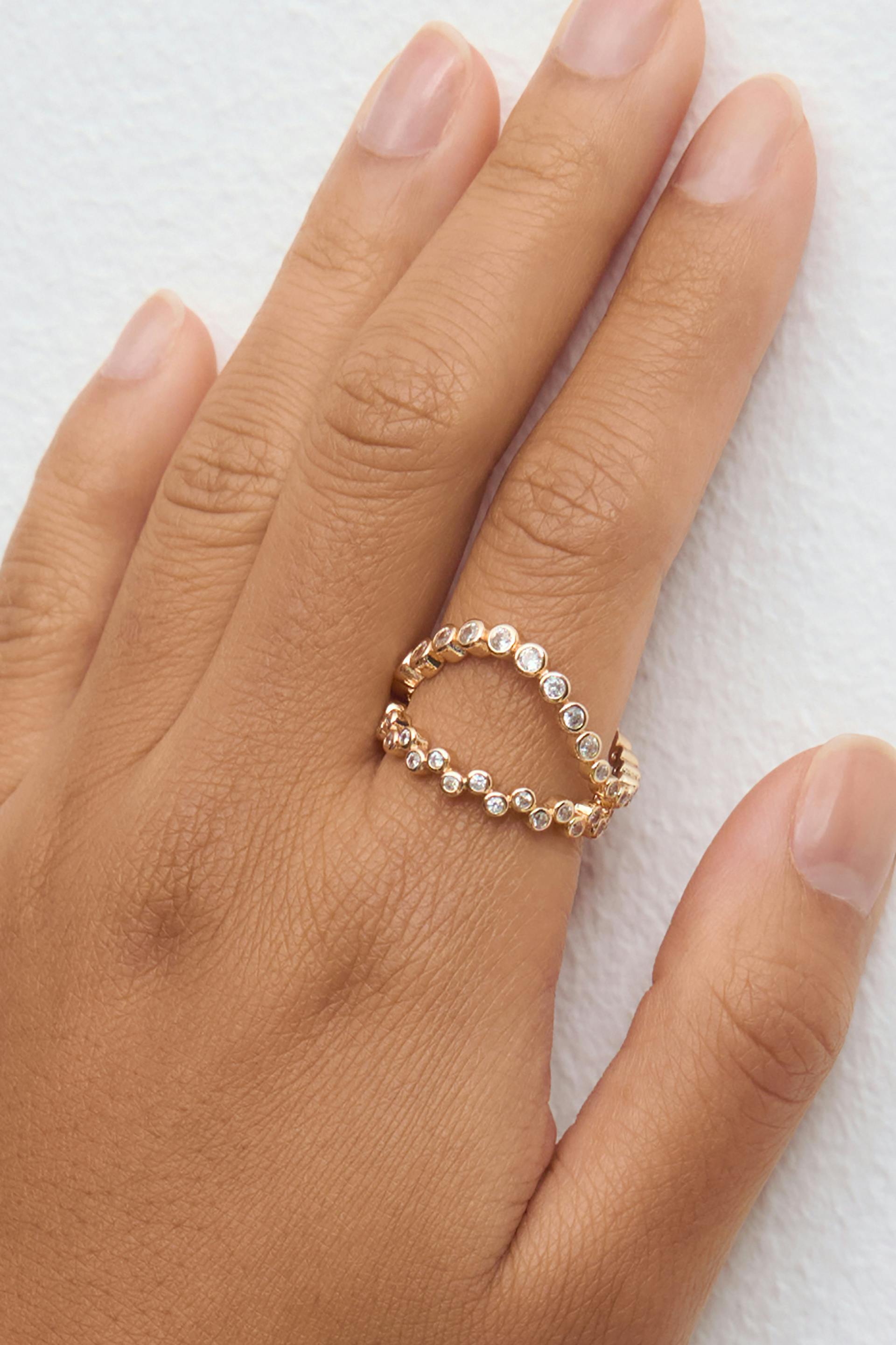 Kulta avoin kaksirivinen rengas, jossa kehysasennetut pyöreät kirkkaat jalokivet.