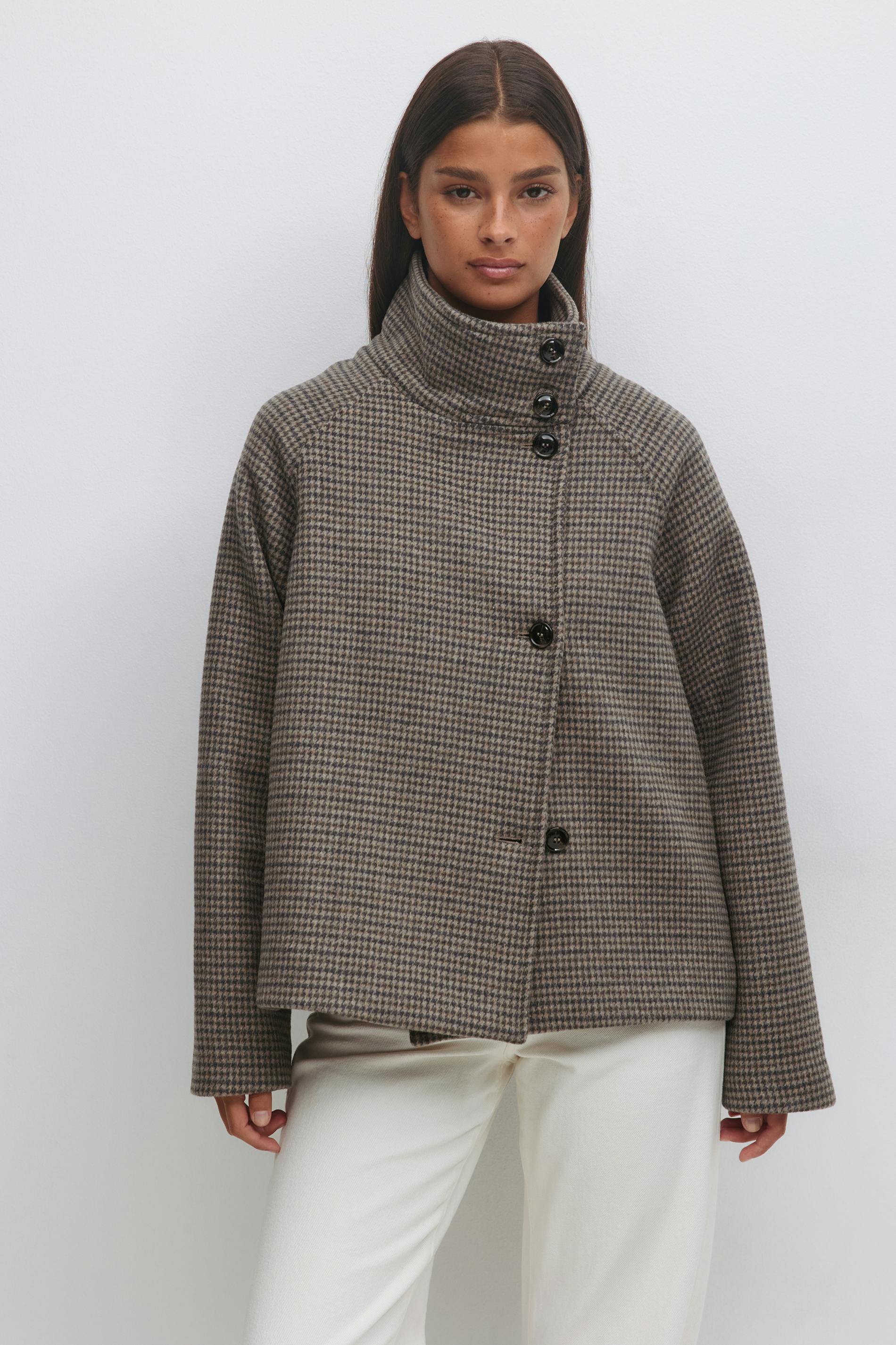 Højhalset, dobbeltradet, cropped uldfrakke i brun mikro-hundestøv med sorte knapper og lange ærmer, sat sammen med off-white bukser med lige ben.