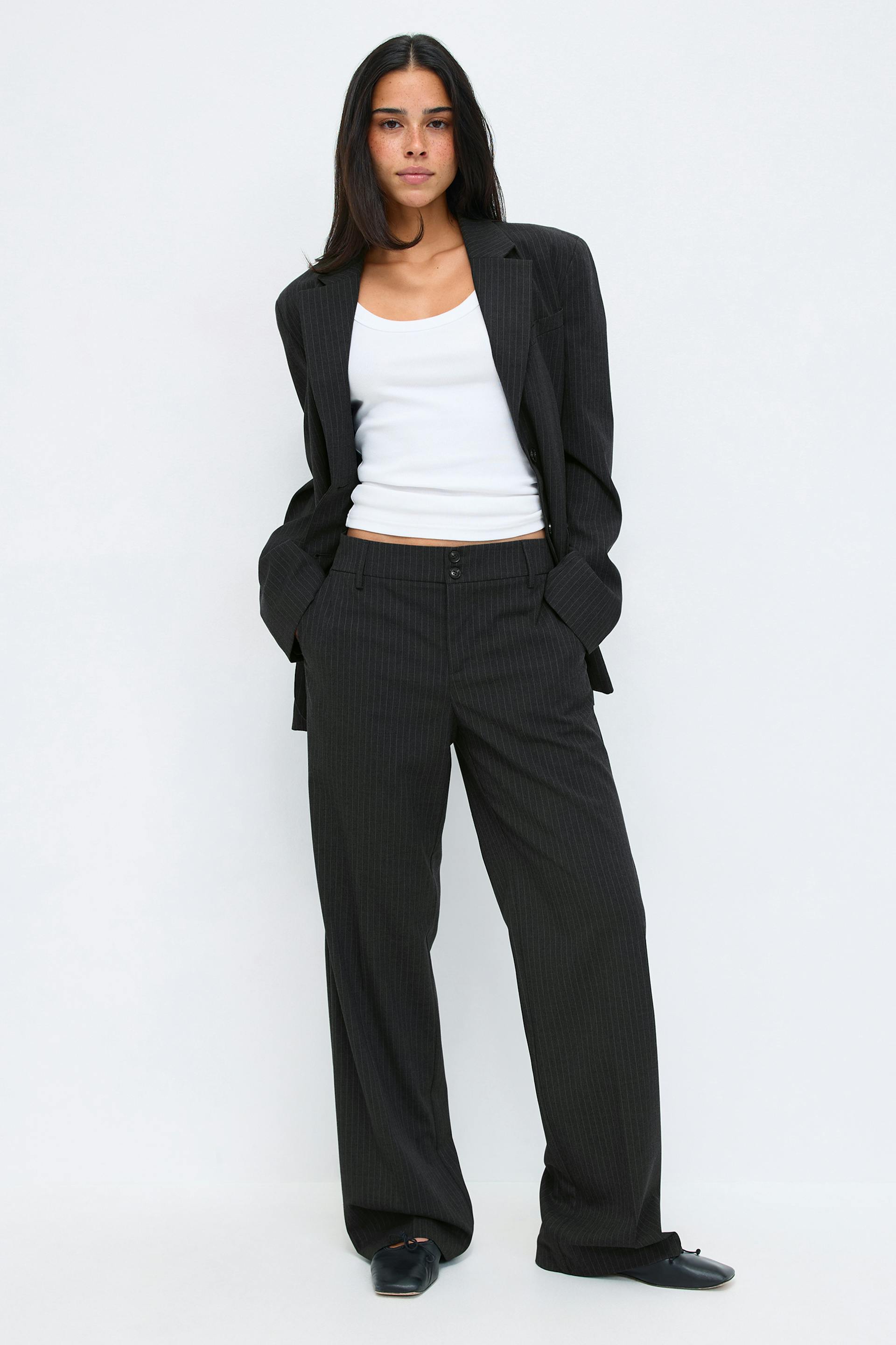 Charcoal pinstripe oversized blazer with matching wide-leg trousers, paired with a white tank top and black leather flats.