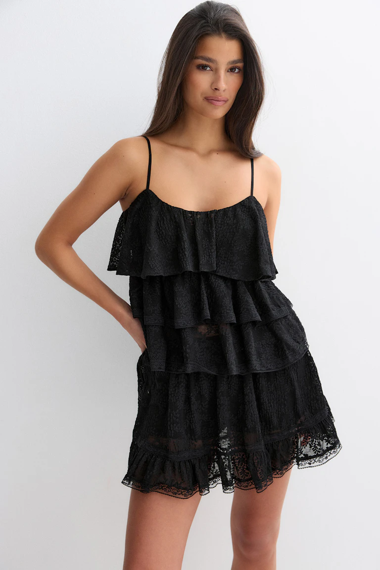 Black lace tiered mini dress with thin spaghetti straps, layered ruffle bodice and scalloped lace hem.