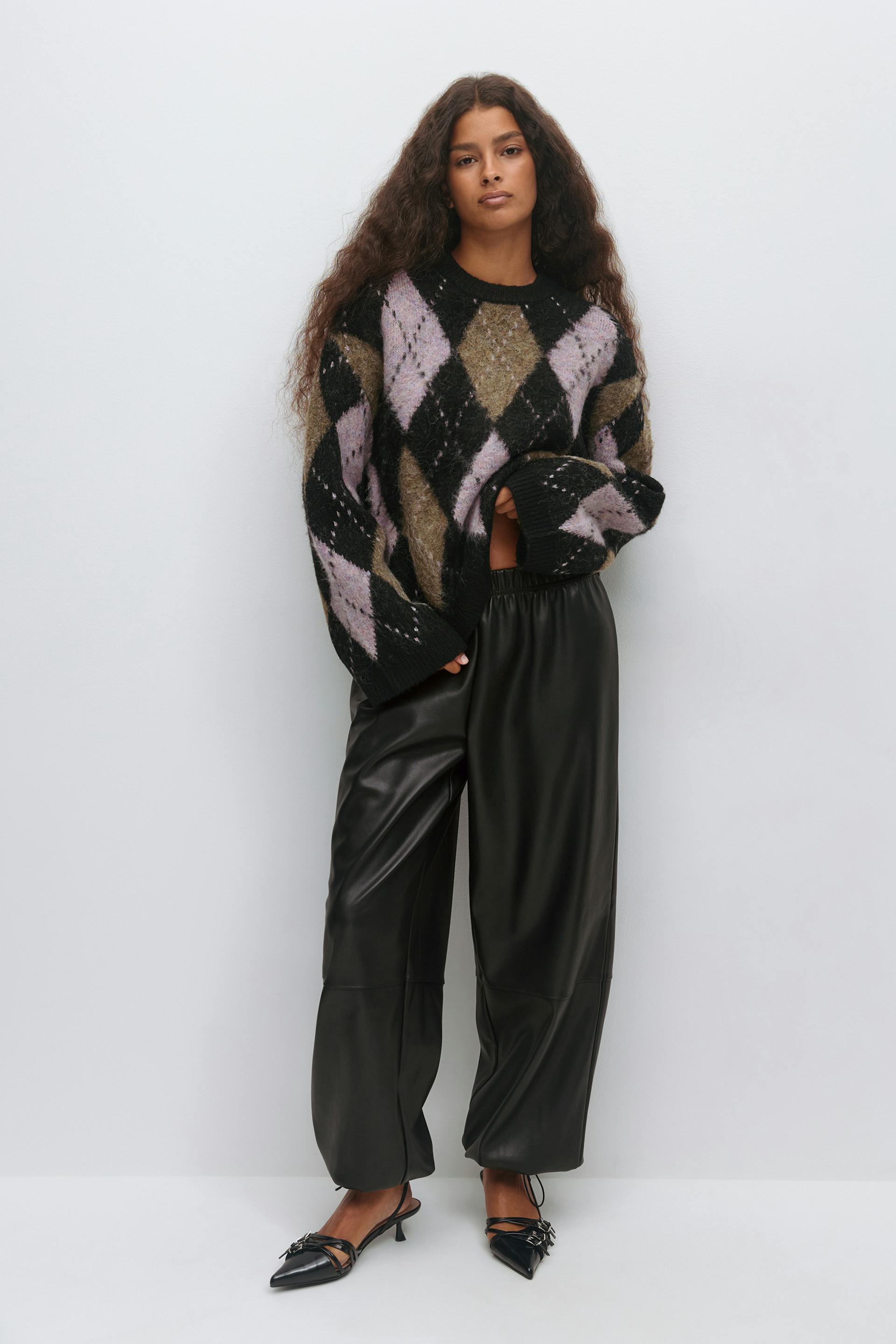 Oversized fuzzy argyle sweater in black, lilac and olive, black faux‑leather wide‑leg trousers with elastic waistband, and black pointed‑toe slingback kitten‑heel shoes with strap detailing.
