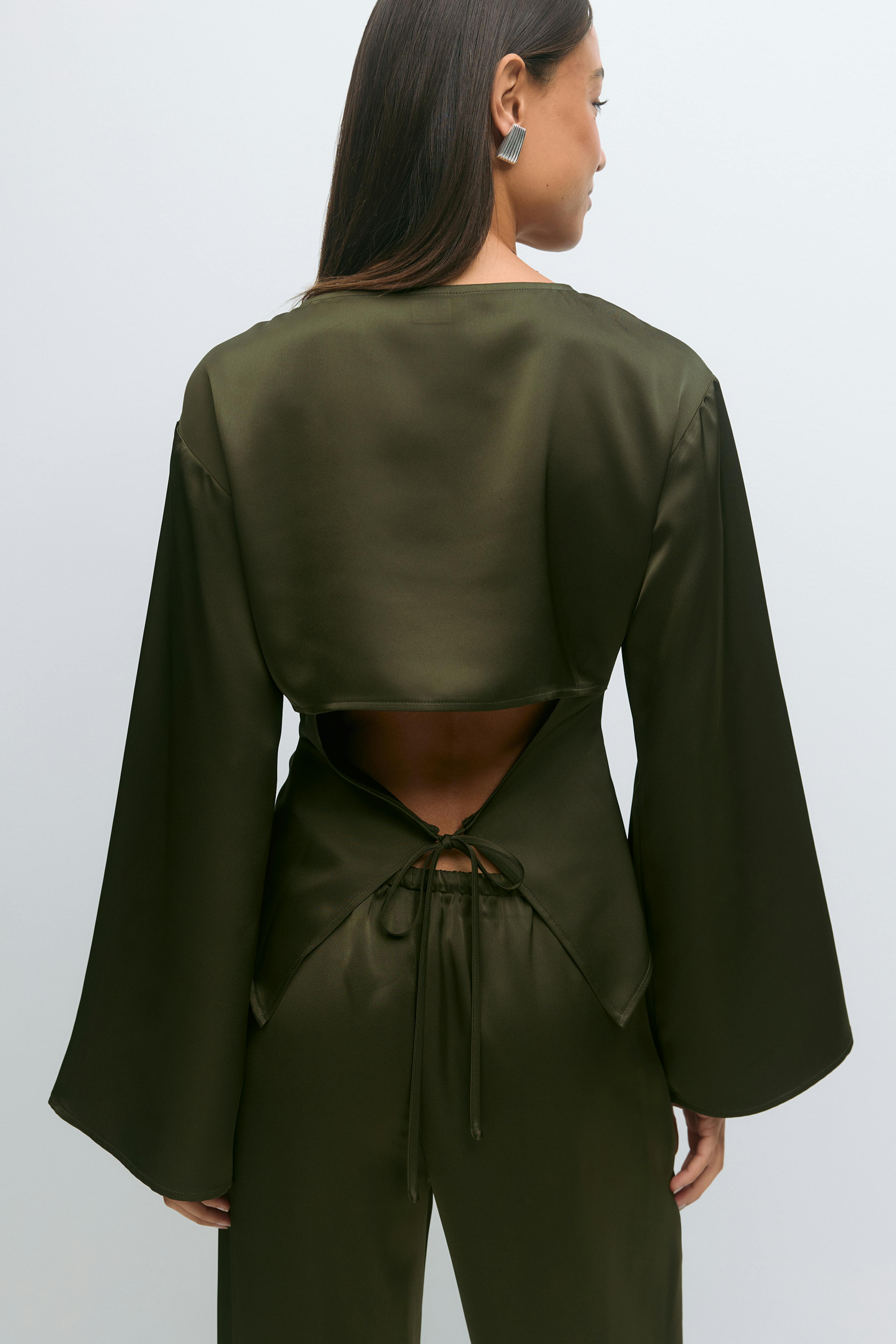 Olive-green satin long-sleeve top with wide sleeves and a triangular open-back detail tied at the waist, paired with matching olive-green satin trousers.