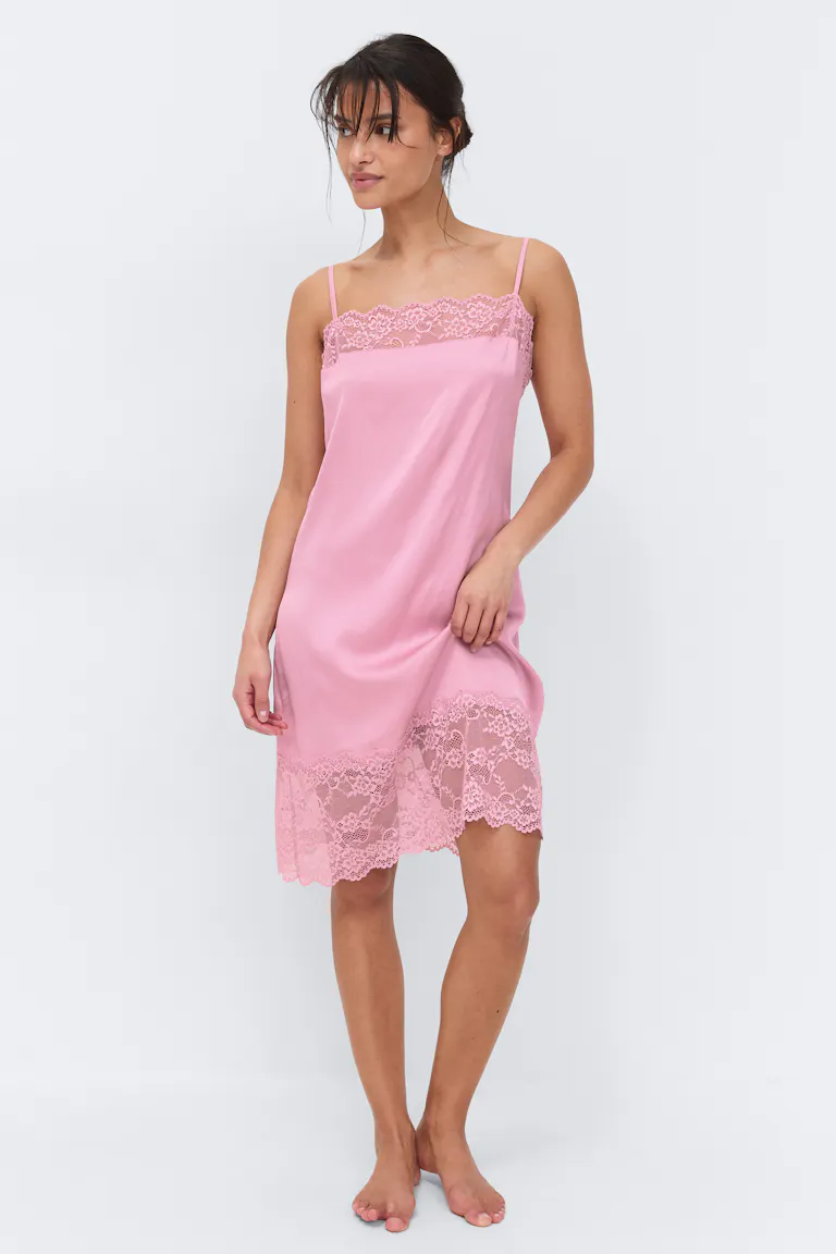 Knee-length pink satin slip dress with thin spaghetti straps and floral lace trim at the neckline and hem.