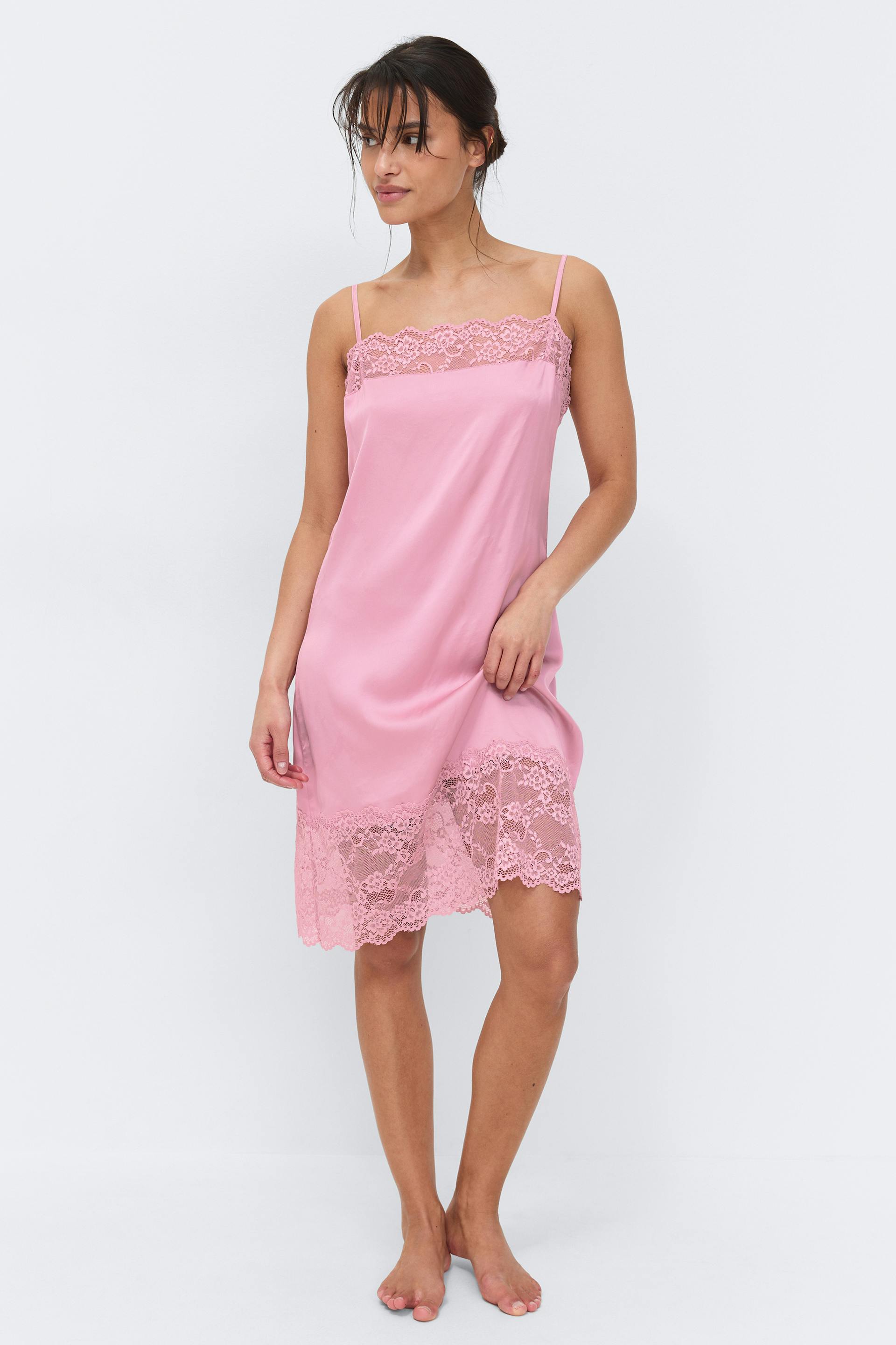 Knee-length pink satin slip dress with thin spaghetti straps and floral lace trim at the neckline and hem.