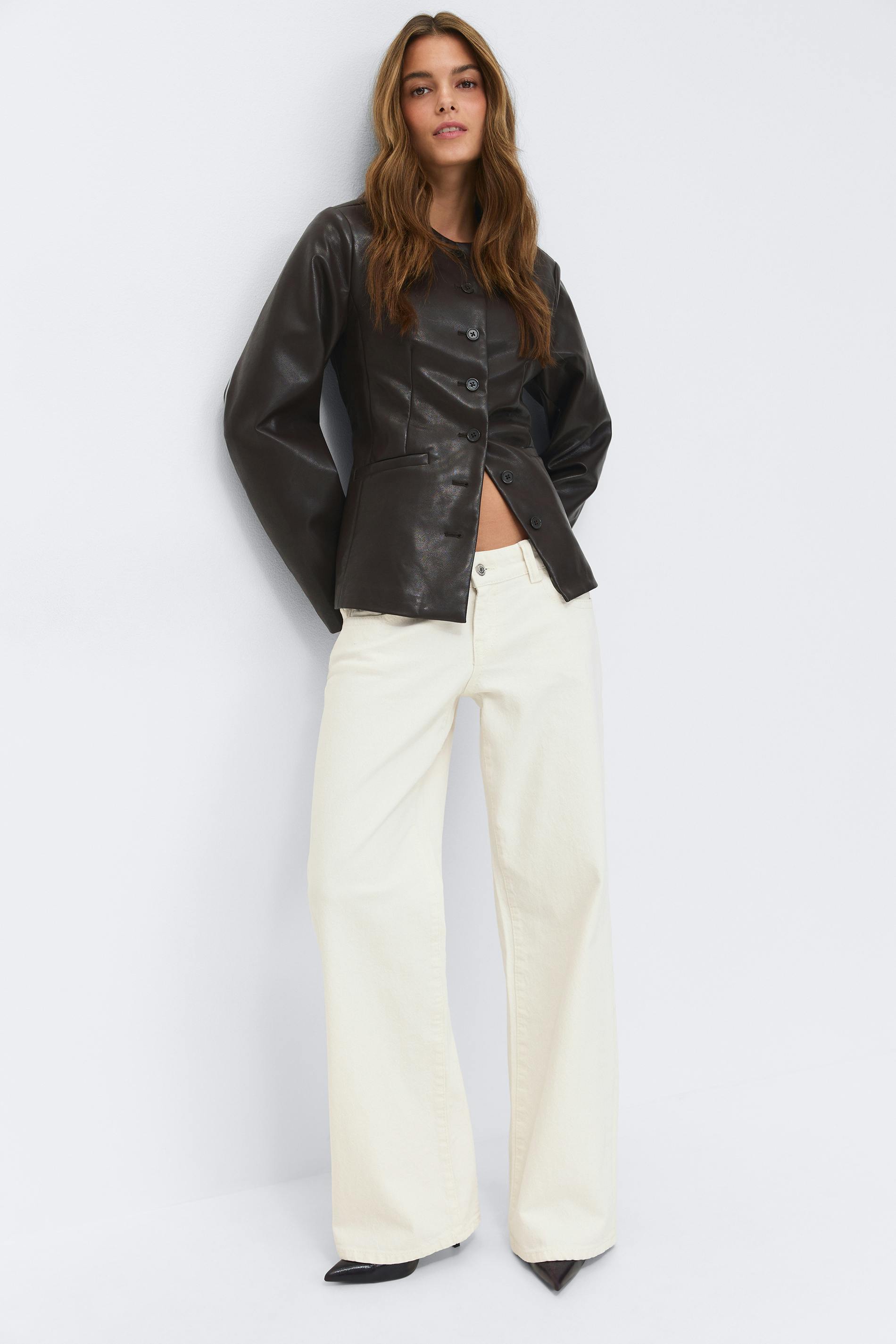 White short-sleeve crewneck T‑shirt tucked into off-white wide-leg trousers, accessorized with a slim black belt with gold buckle, black mesh pointed-toe flats, and gold hoop earrings.