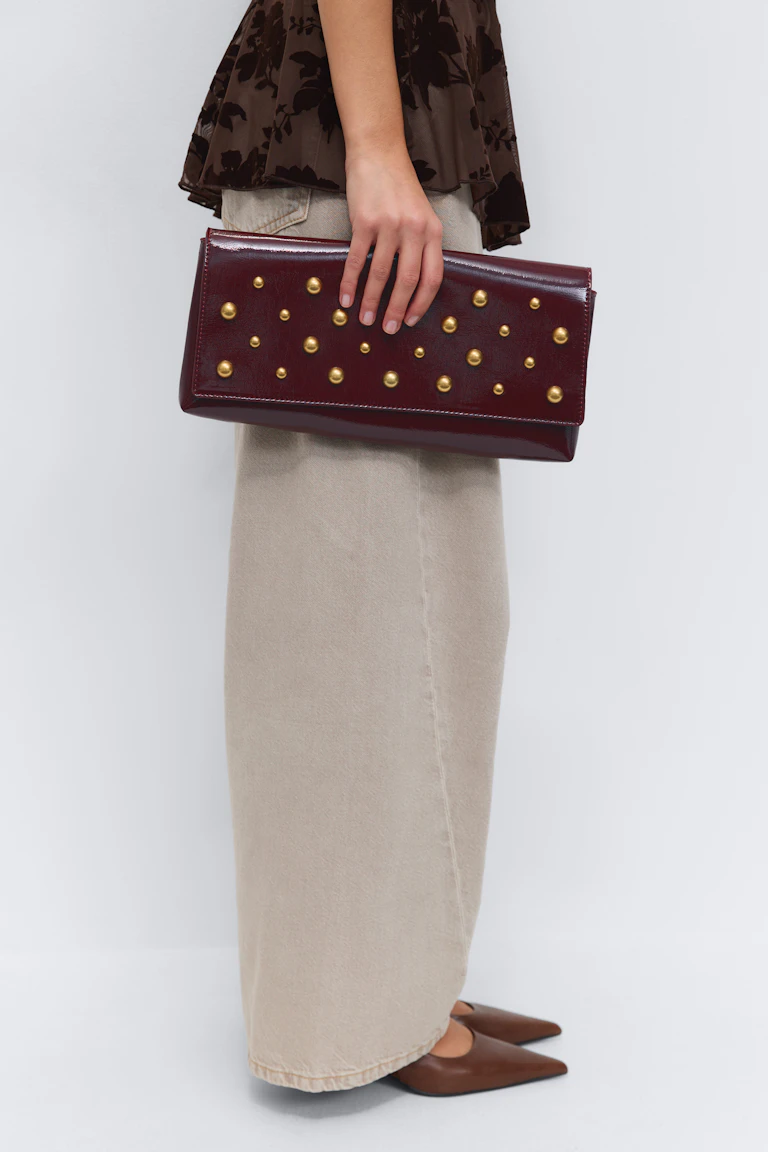 Mørkebrun blomstermønstret peplumtop; lang beige maxinederdel; brune spidse sko; bordeauxfarvet clutch i laklæder med guldnitter.