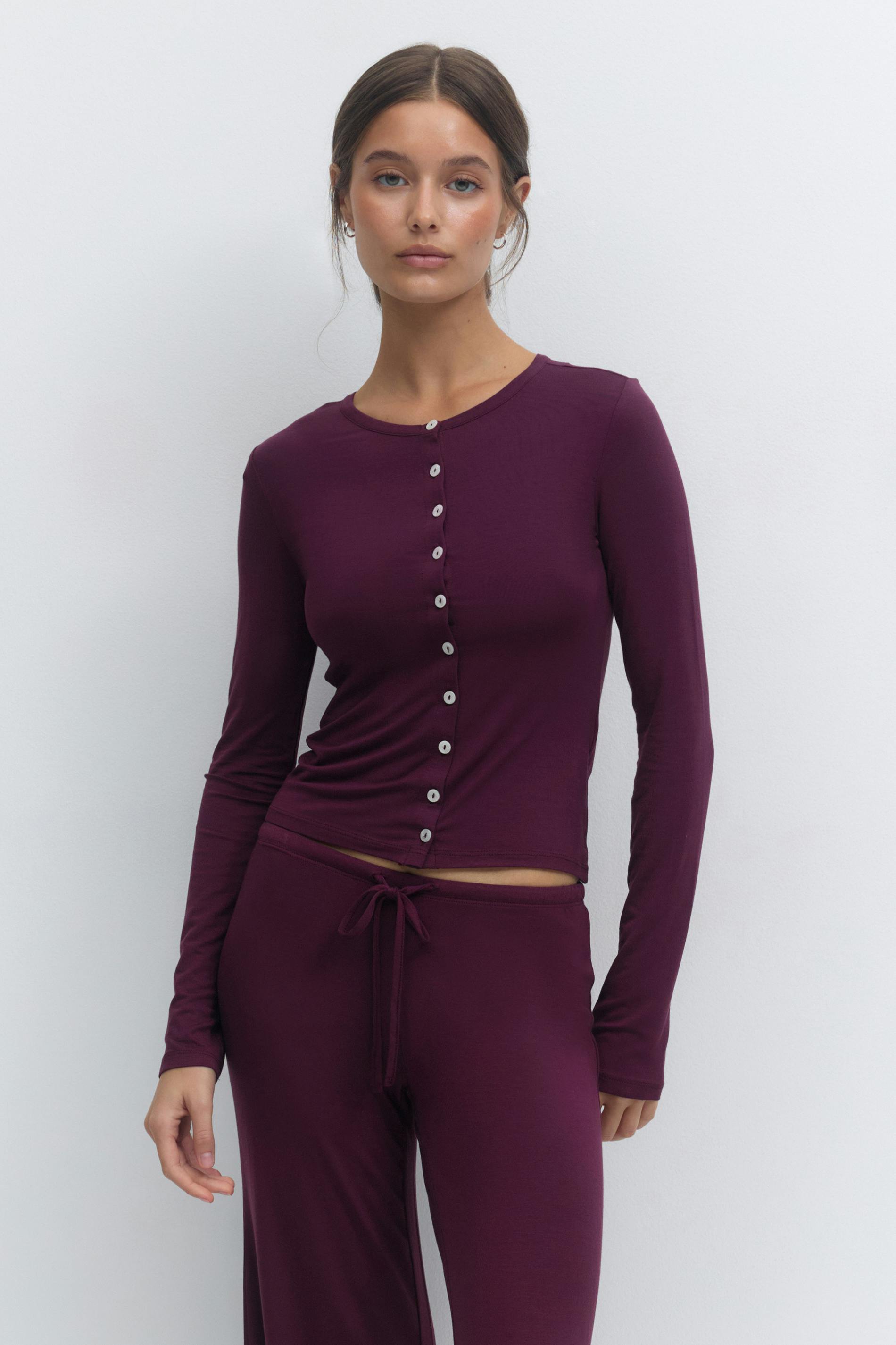 Deep plum long-sleeve fitted button-front top with small round contrast buttons, slightly cropped, paired with matching drawstring lounge pants.