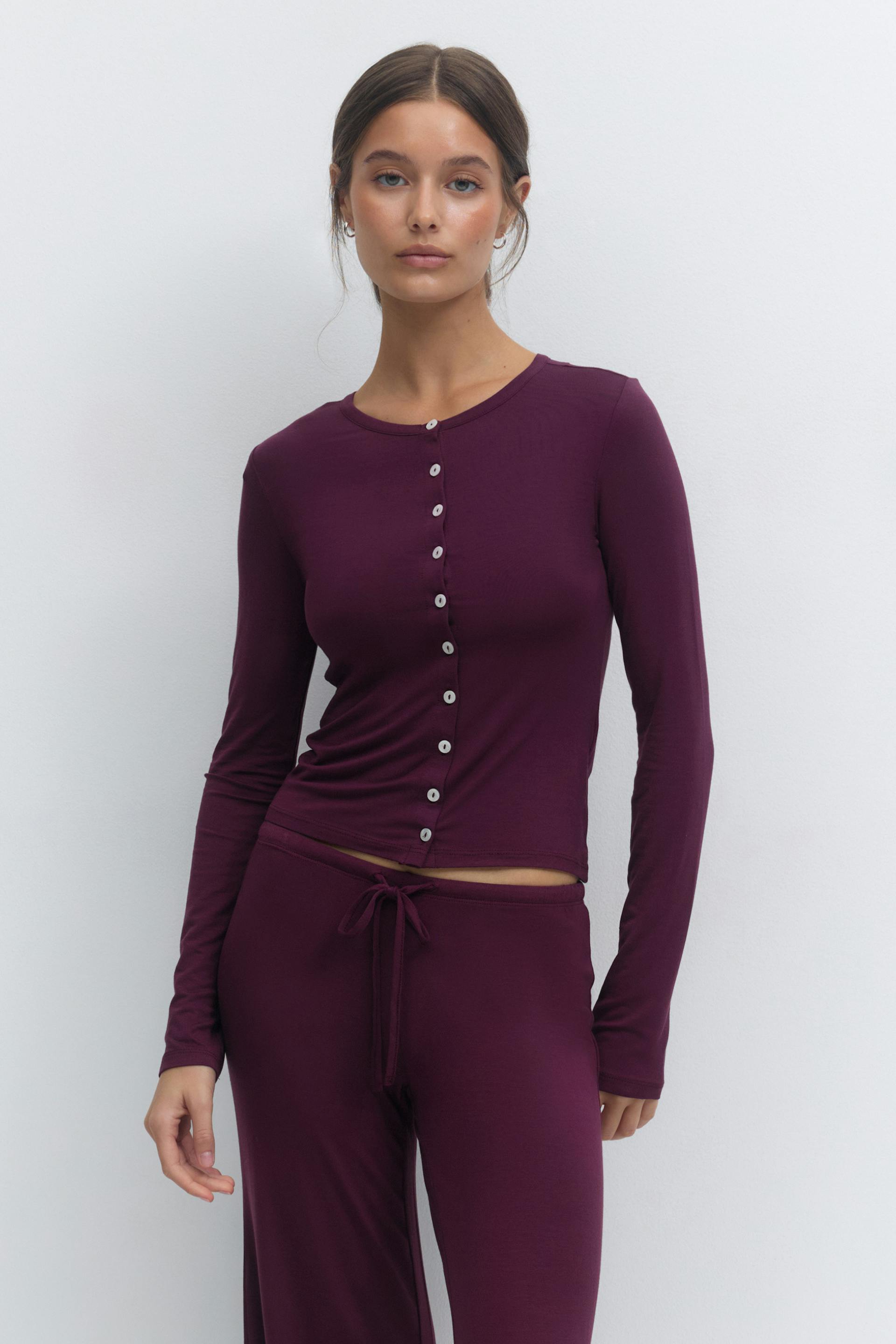 Deep plum long-sleeve fitted button-front top with small round contrast buttons, slightly cropped, paired with matching drawstring lounge pants.