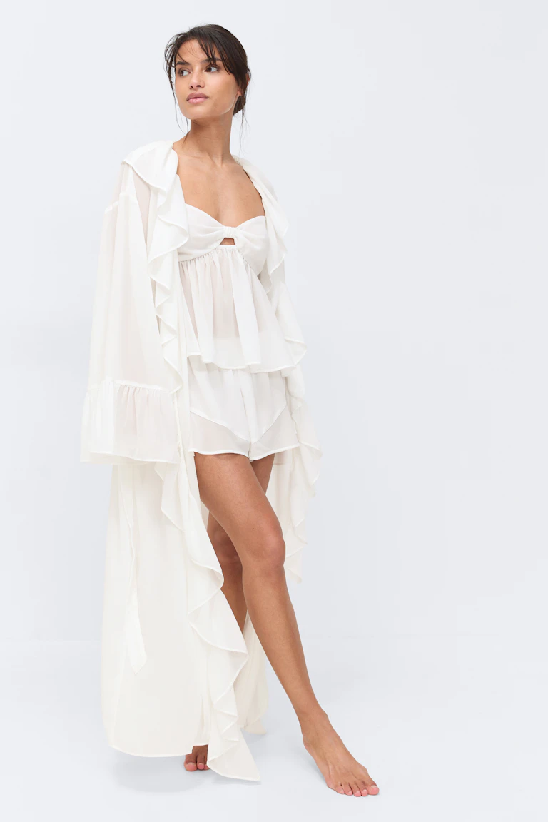 Ivoorkleurige gladde chiffon kamerjas met laagjes over een bijpassende gladde babydoll bandeau top met een knoop aan de voorkant en een sleutelgat, gecombineerd met een bijpassende gladde short.