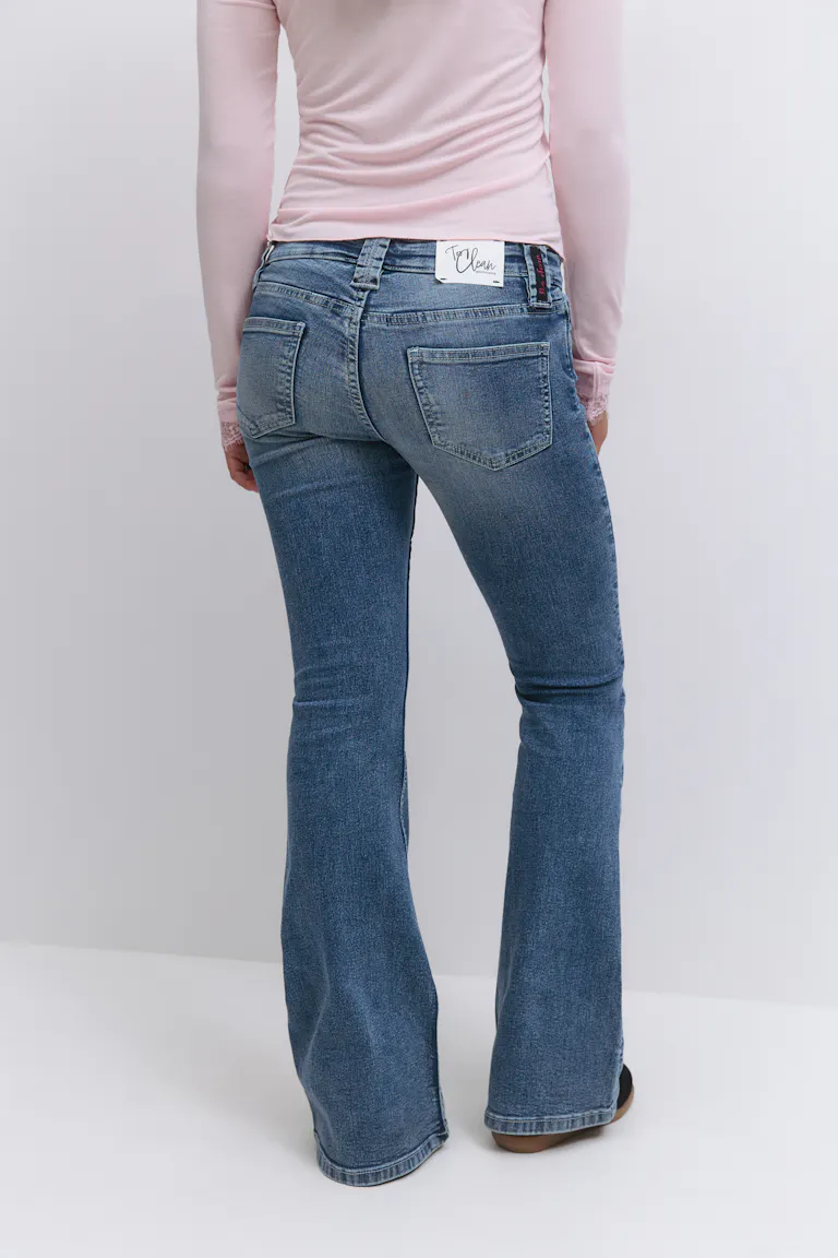 Lyserød langærmet top sat ned i mellemvaskede bootcut-jeans med påsatte baglommer og diskret fading.