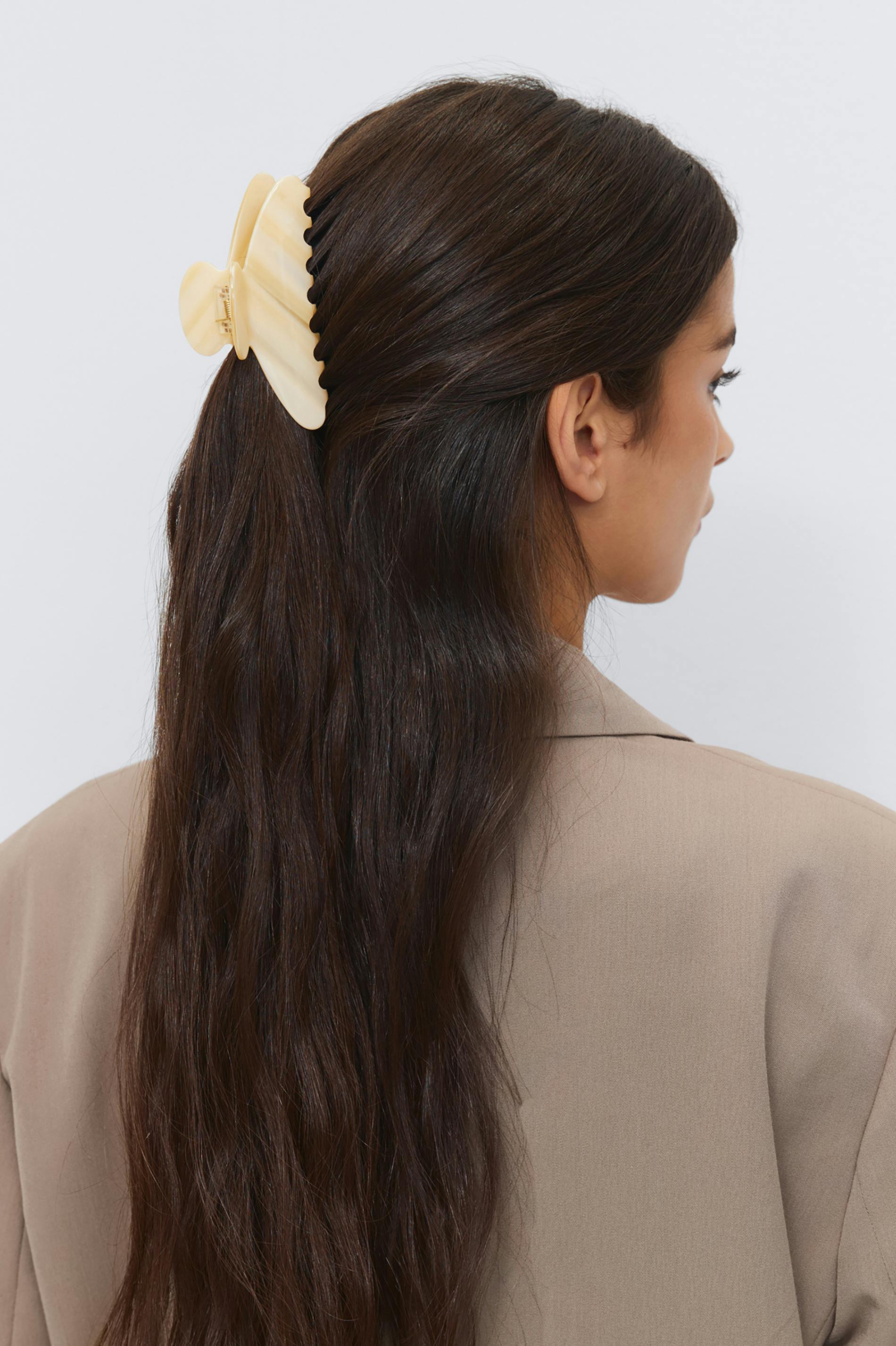 Light beige tailored blazer and large cream-colored scalloped hair claw clip.