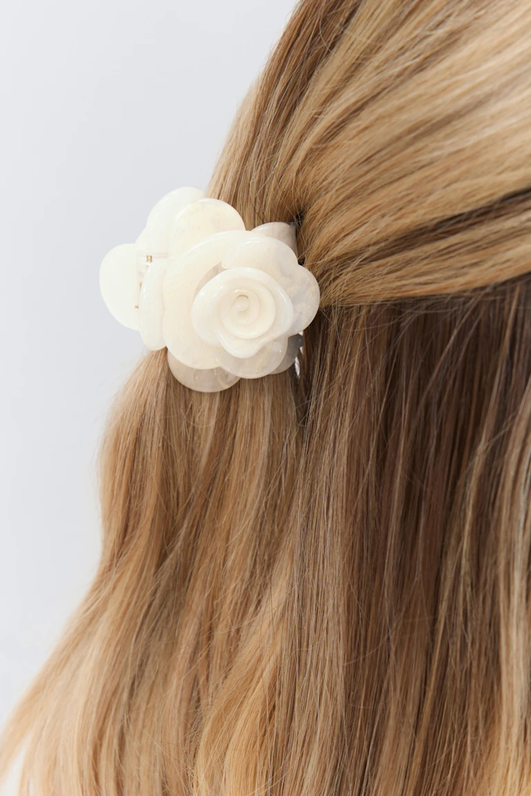 Pince à cheveux en résine marbrée ivoire pour fixer une coiffure à mi-hauteur.