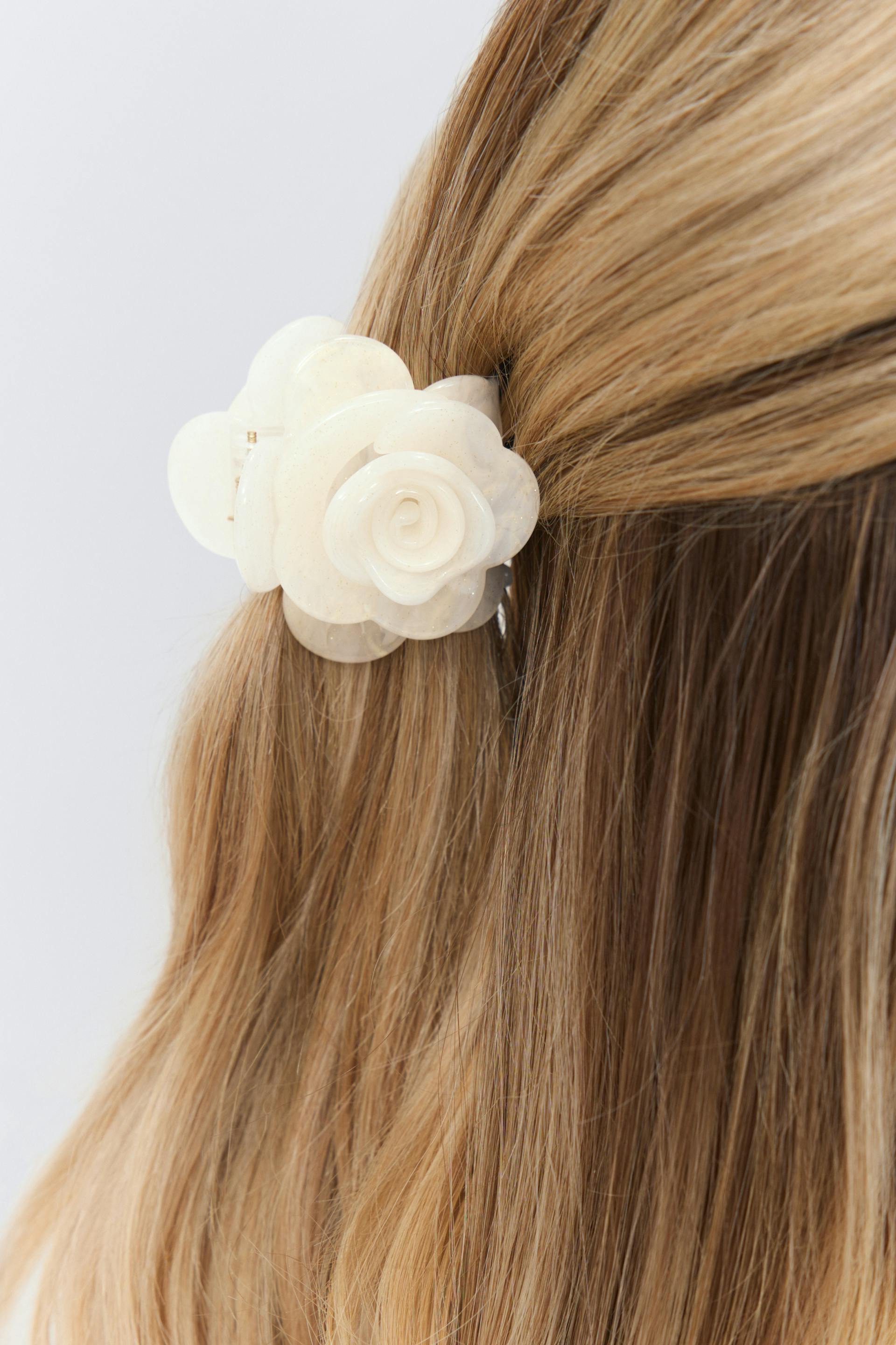 Ivory marbled resin flower hair clip securing a half-up hairstyle.