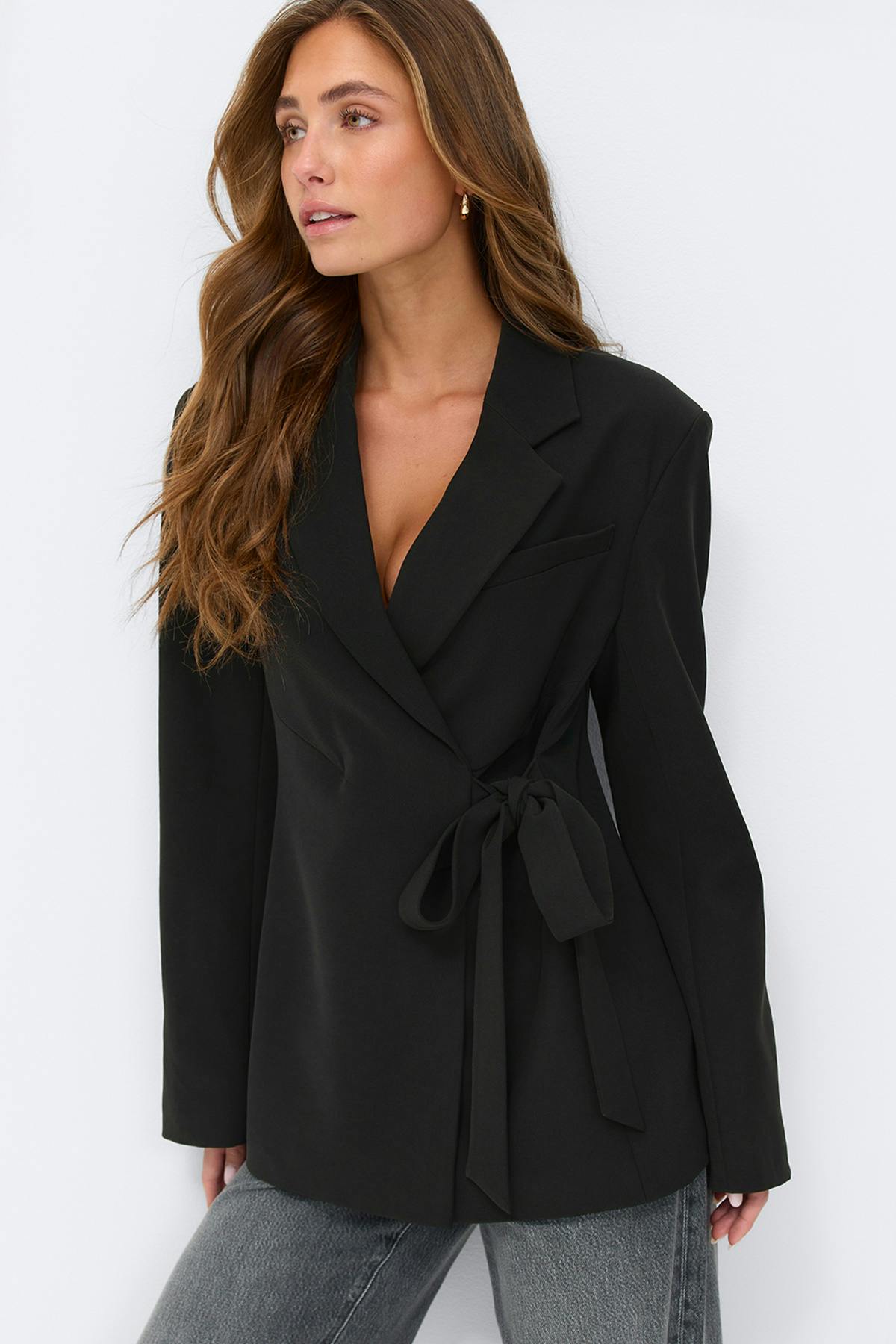 Musta kietaisublakkeri, jossa on lovetut läpyset ja vyötärönauha sivulla, yhdistettynä haalistuneisiin harmaisiin farkkuihin.