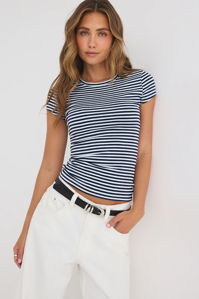 Een marineblauw-wit gestreept shirt met korte mouwen, gecombineerd met een witte broek en een zwarte riem.