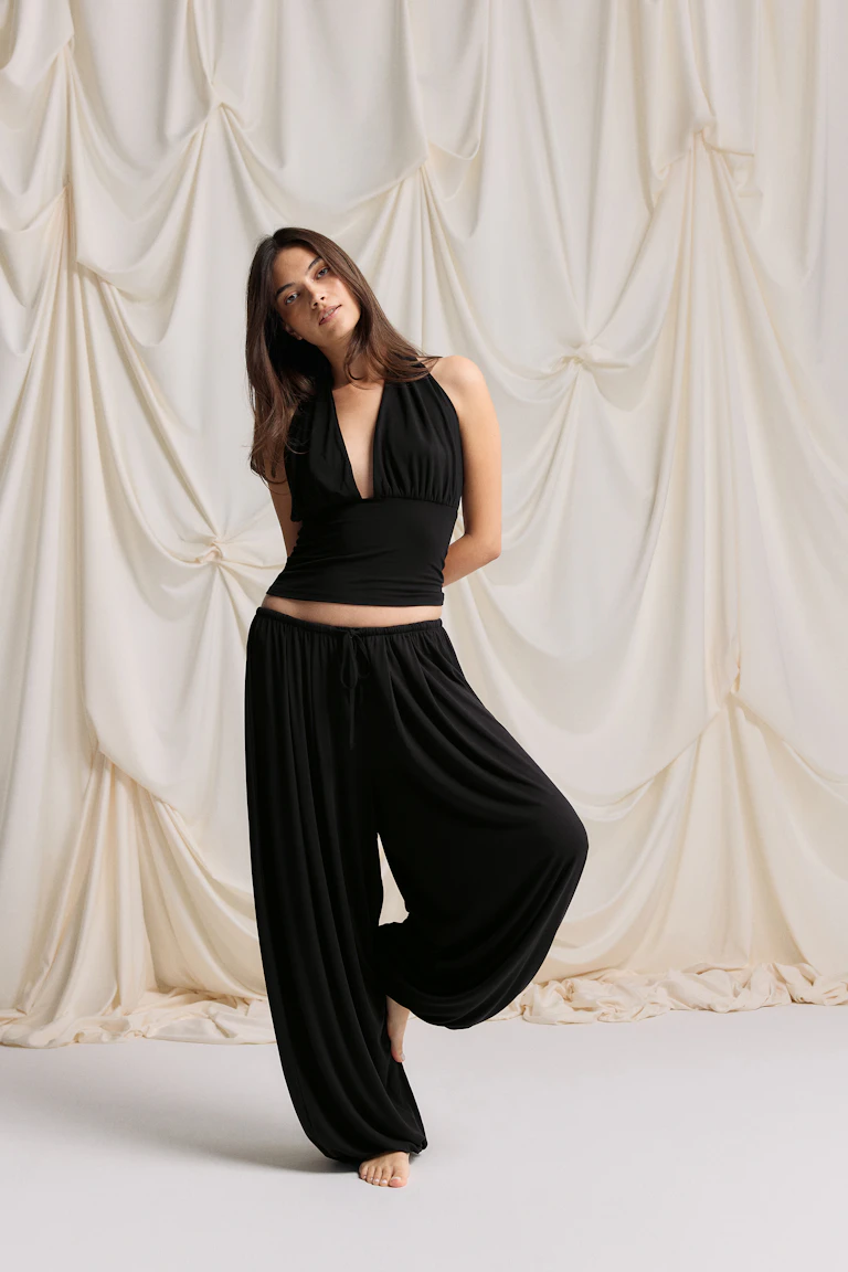 Top noir à col licou, décolleté en V plongeant et taille ajustée, associé à un pantalon harem noir assorti à cordon de serrage à jambe large.