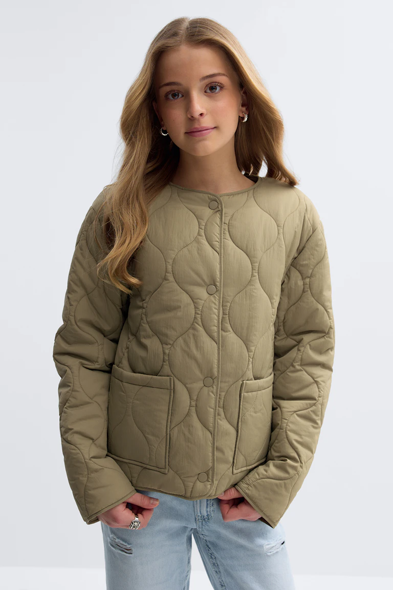 Khaki gewatteerd jack met drukknoopsluiting met ronde hals, lange mouwen, twee opgestikte zakken aan de voorkant en golvend quiltwerk, gecombineerd met een licht verwassen distressed jeans.