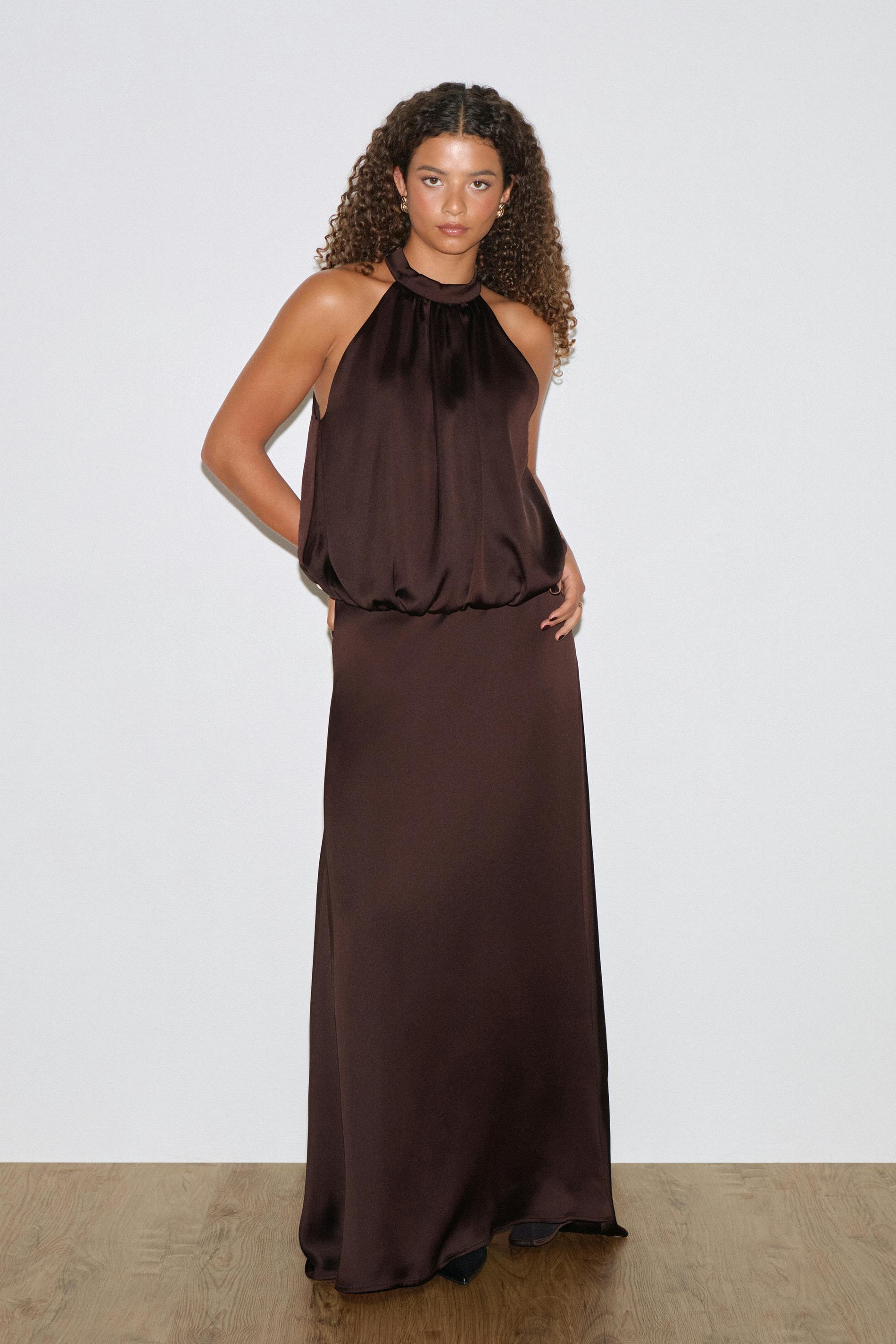 Sleeveless halter-neck dark brown satin evening gown with a gathered high neckline, blouson bodice and a floor‑length column skirt.