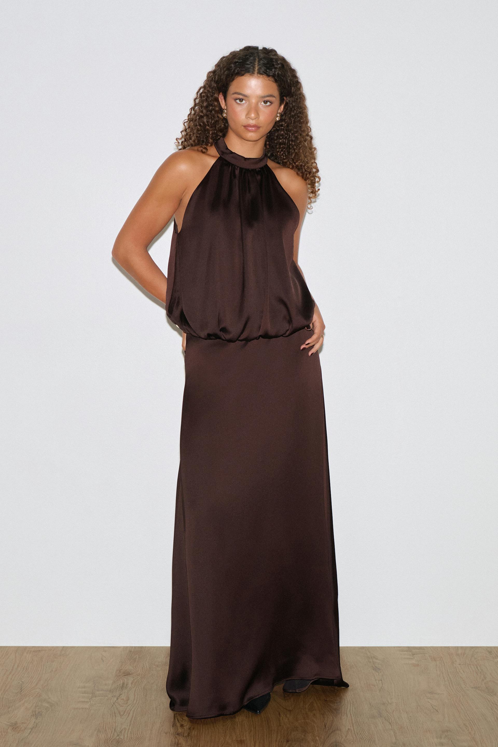 Sleeveless halter-neck dark brown satin evening gown with a gathered high neckline, blouson bodice and a floor‑length column skirt.