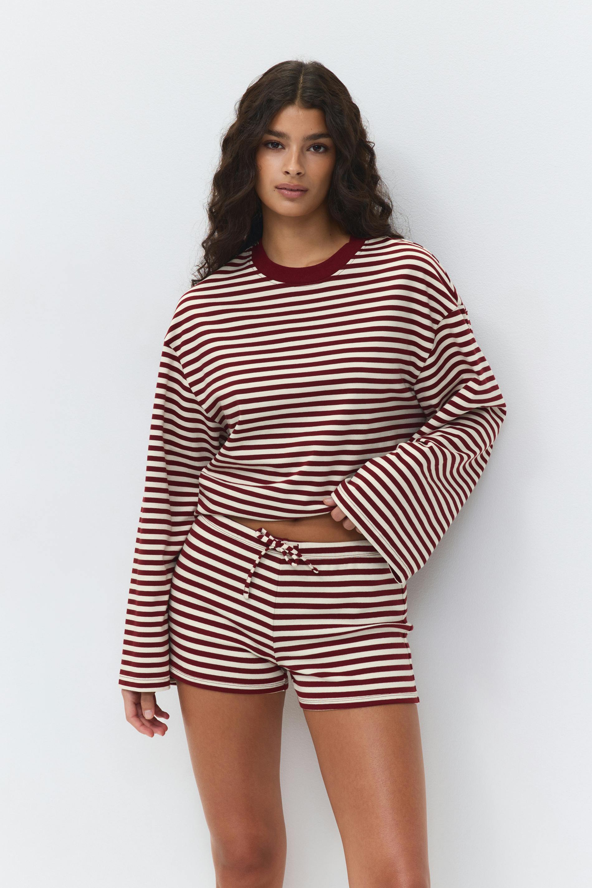 Maroon-and-white horizontal striped long-sleeve crewneck top with wide sleeves, paired with matching drawstring striped shorts.