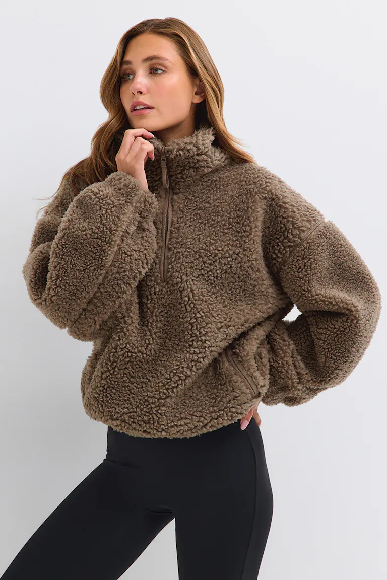 Brauner Pullover aus Teddy-Fleece mit schwarzen Leggings.